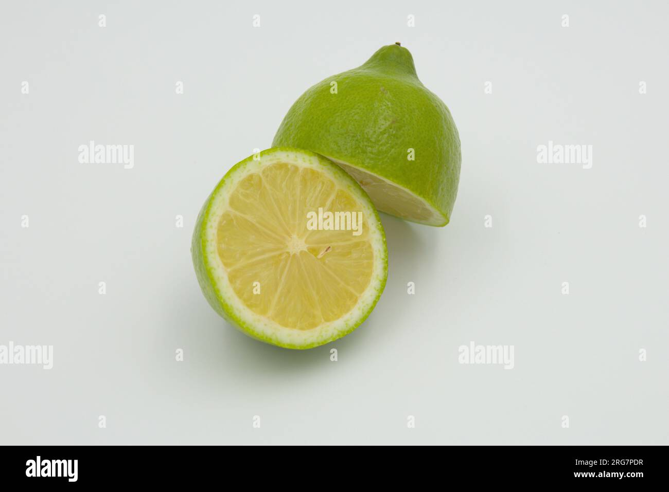 Trainare metà di un limone verde su sfondo bianco Foto Stock