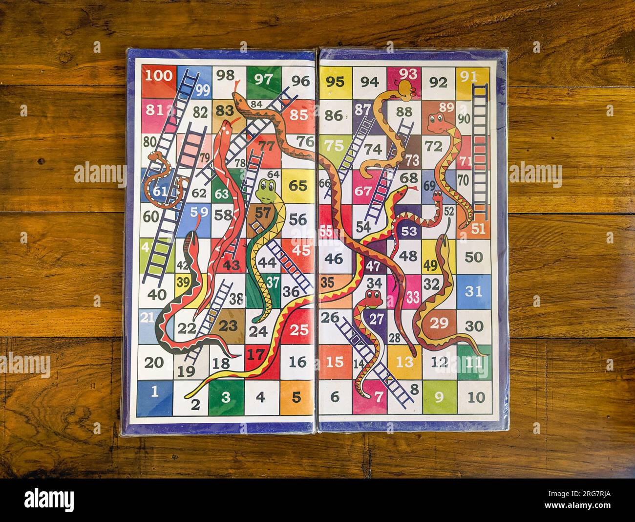 primo piano di una versione colorata di un gioco da tavolo multigiocatore con serpenti e scale su uno sfondo di legno Foto Stock