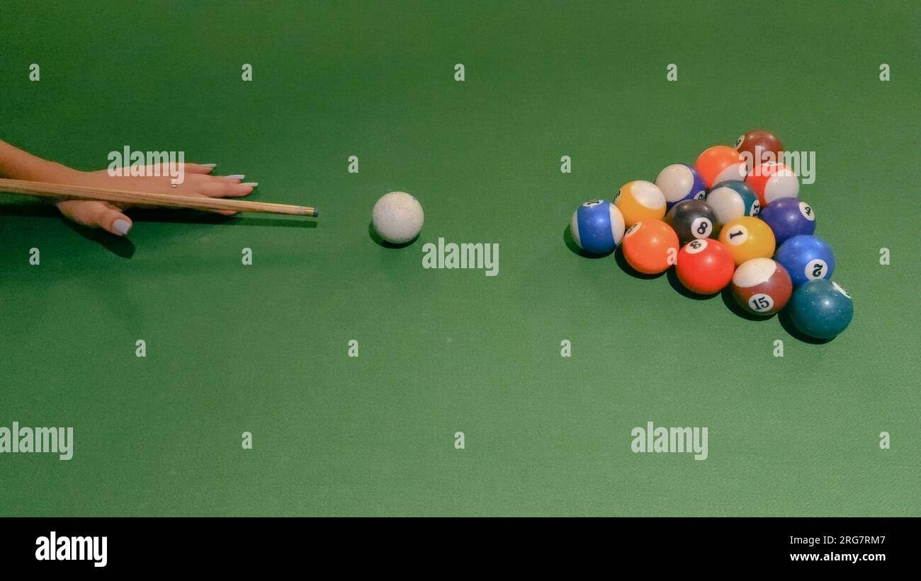 mano di donna che gioca in un biliardo verde tavolo da biliardo a otto palline pronto a colpire e segnare Foto Stock