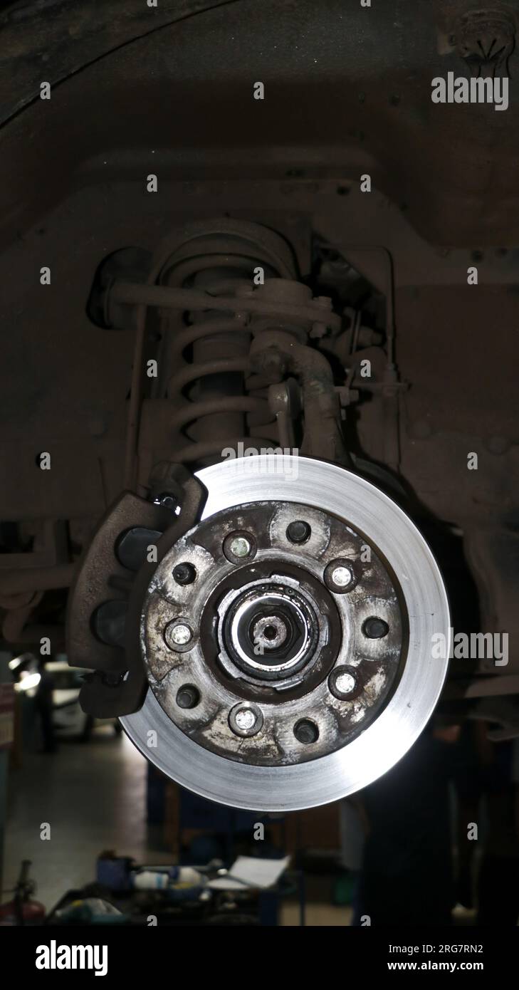 freno a disco e pinza di stazionamento idraulici vecchi e sporchi di un'auto sottoposta a manutenzione in una stazione di servizio Foto Stock