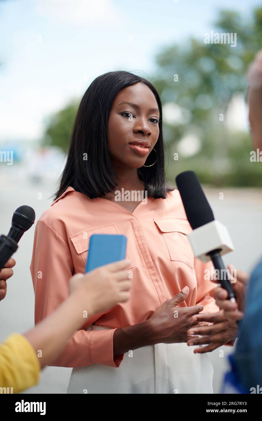 Ritratto di donna elegante nera che parla con i giornalisti all'aperto Foto Stock