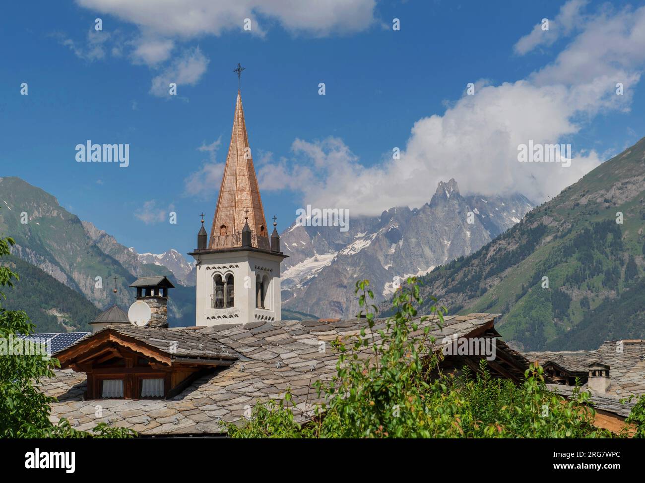 Vista sul campanile di ottone di una chiesa di un vilage italiano nella valle d'aosta su uno sfondo montuoso Foto Stock