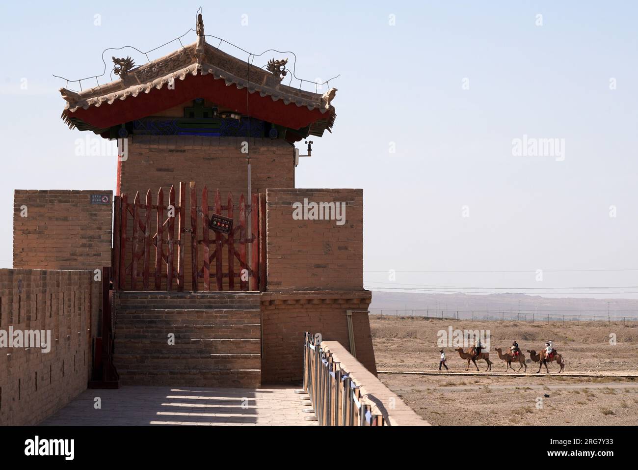 Jiayuguan, provincia cinese del Gansu. 7 agosto 2023. I turisti cavalcano a dorso di cammello fuori dal passo Jiayu nella città di Jiayuguan, provincia del Gansu della Cina nord-occidentale, 7 agosto 2023. Il passo Jiayu, una famosa parte della grande Muraglia costruita durante la Dinastia Ming (1368-1644), ha attirato un numero crescente di visitatori durante la stagione turistica estiva, con oltre 30.000 visitatori al giorno in picco. Crediti: Ma Ning/Xinhua/Alamy Live News Foto Stock