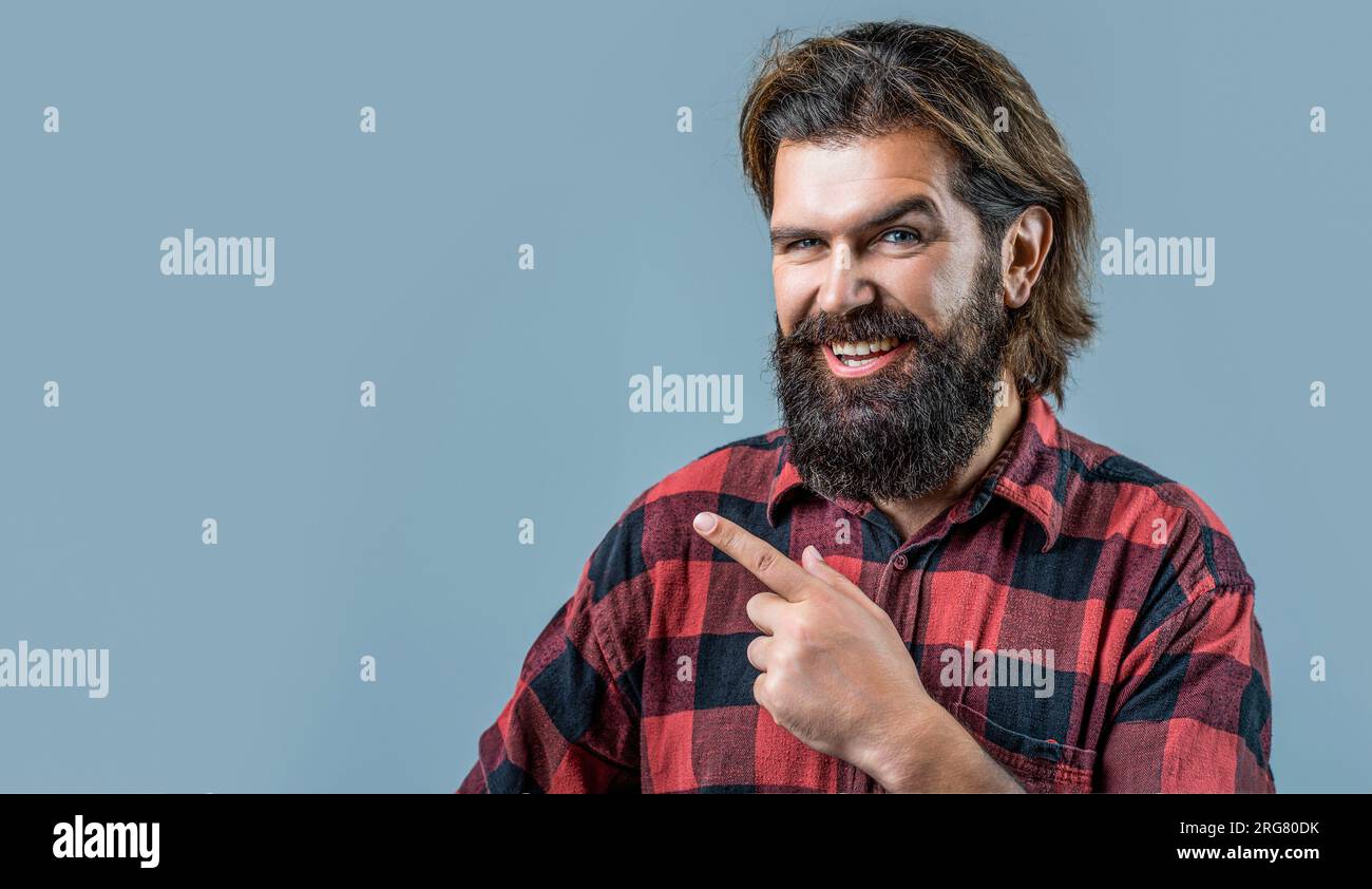 Bell'uomo sorride sul viso, puntando con mano e dito di lato. Ritratto di un uomo manager attraente felice e allegro che mostra il testo dell'annuncio Foto Stock