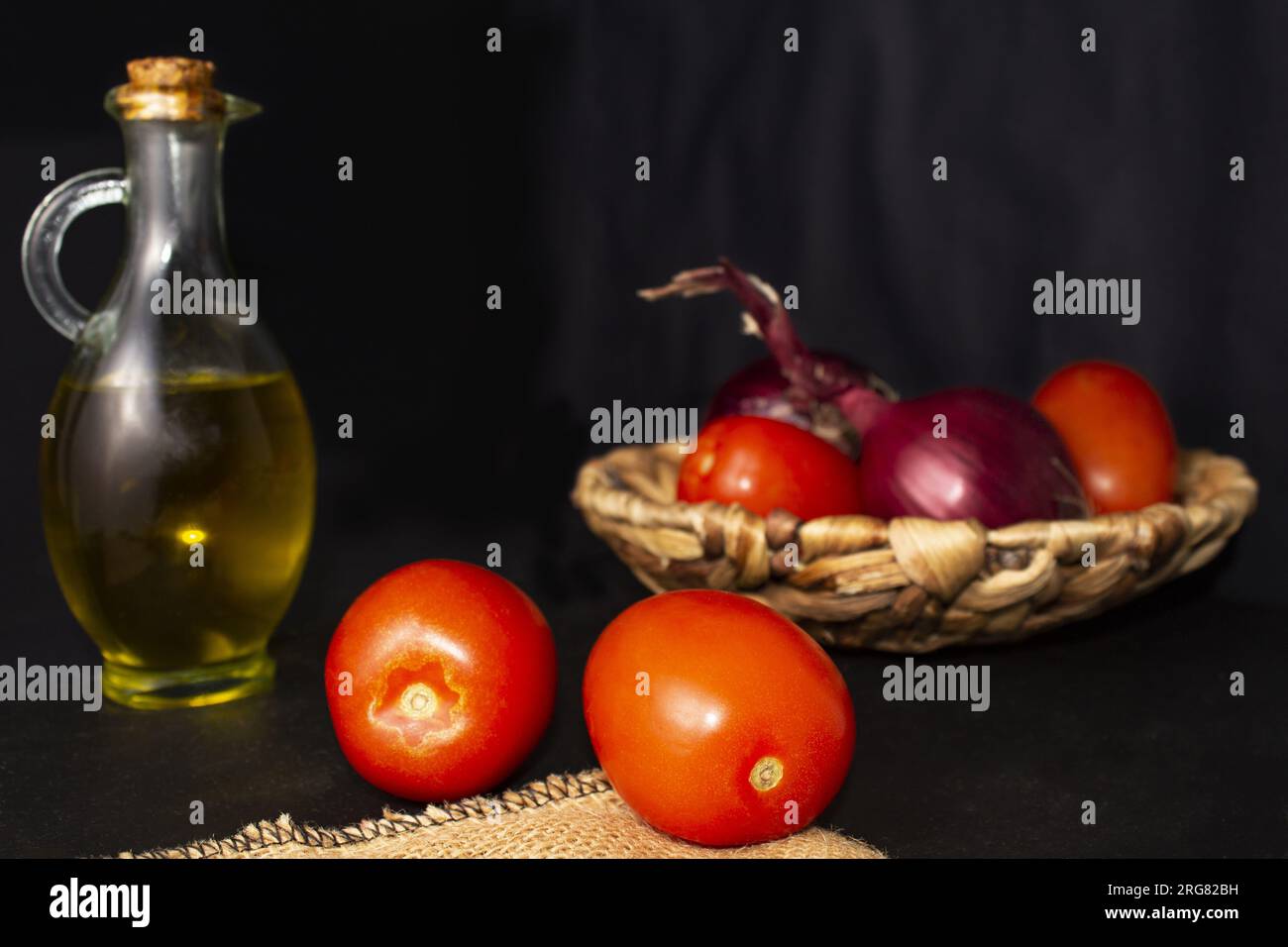 Natura morta colorata di verdure fresche, ingredienti di un'insalata o gazpacho spagnolo. Pomodori rossi pera, cipolla viola e bottiglia di olio d'oliva. Horizont Foto Stock