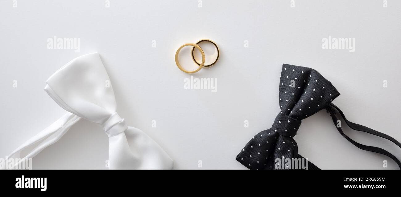 Sfondo concettuale per matrimoni gay con cravatta a pois bianca e nera e fedi nuziali al centro. Vista dall'alto. Foto Stock