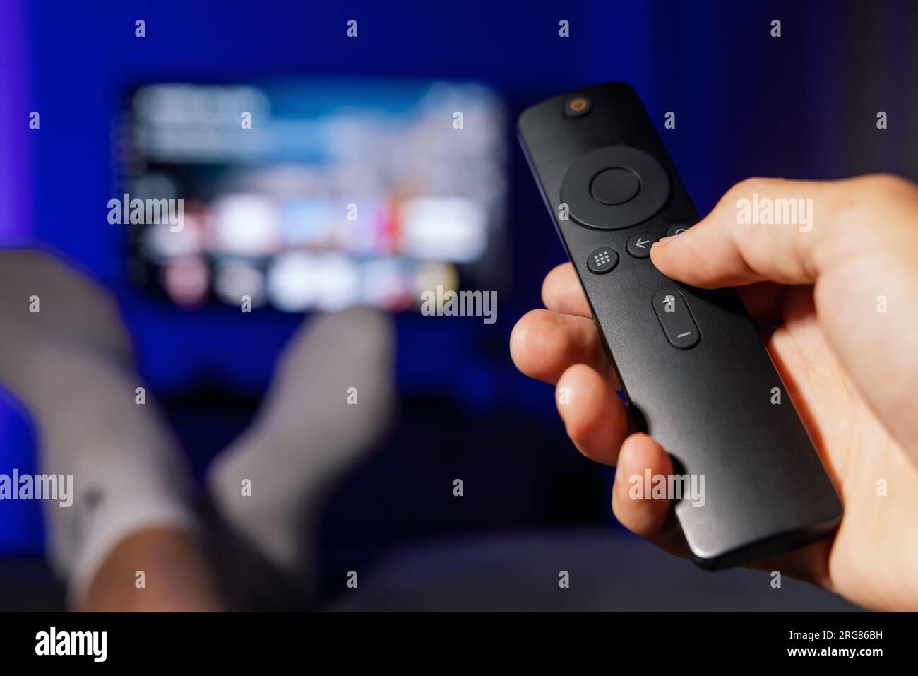 mano con telecomando tv. uomo che guarda contenuti di servizi di streaming a casa Foto Stock