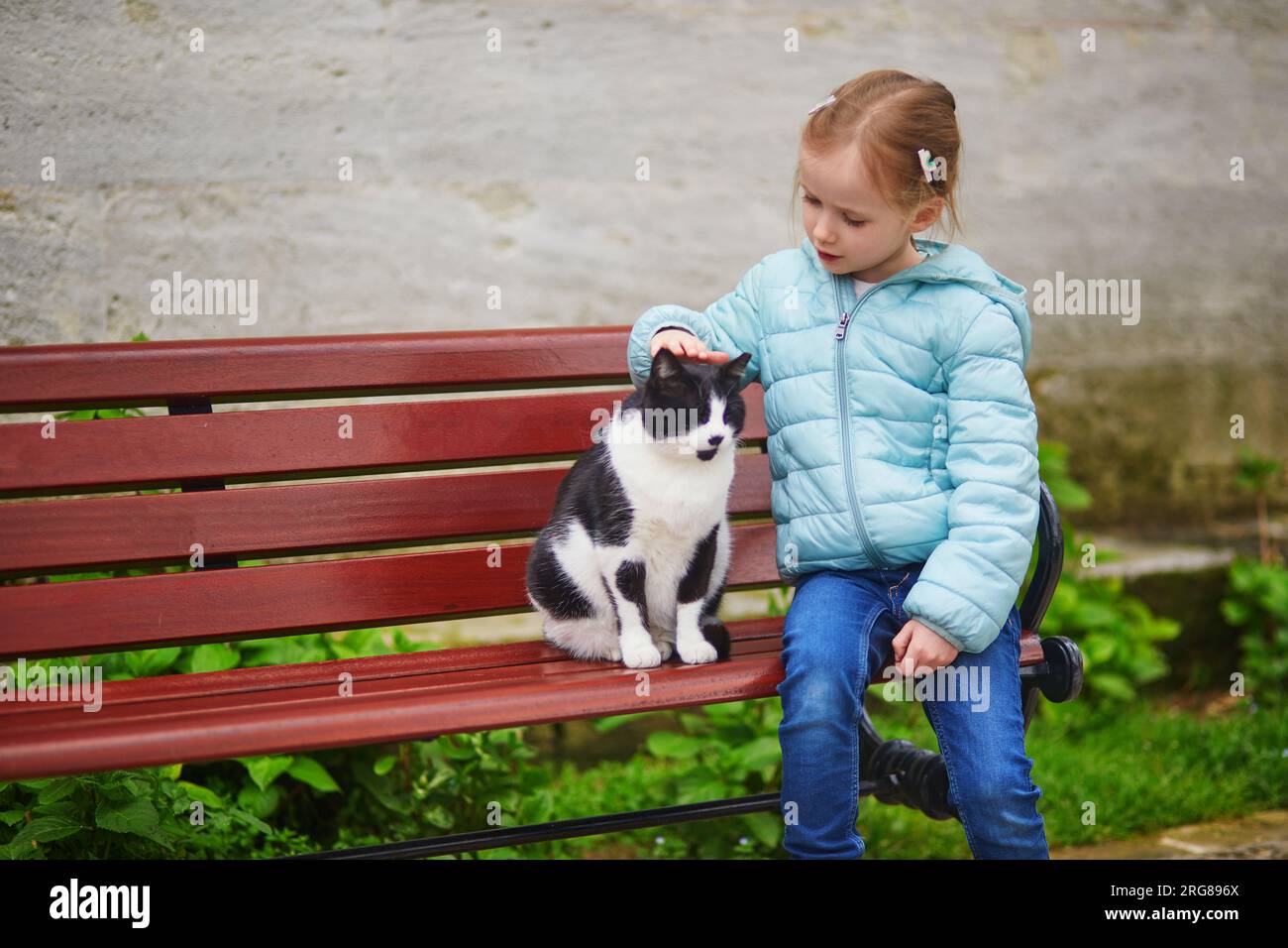 Adorabile bambina in età prescolare che accarezza un gatto nel distretto di Uskudar sul lato asiatico di Istanbul, Turchia Foto Stock