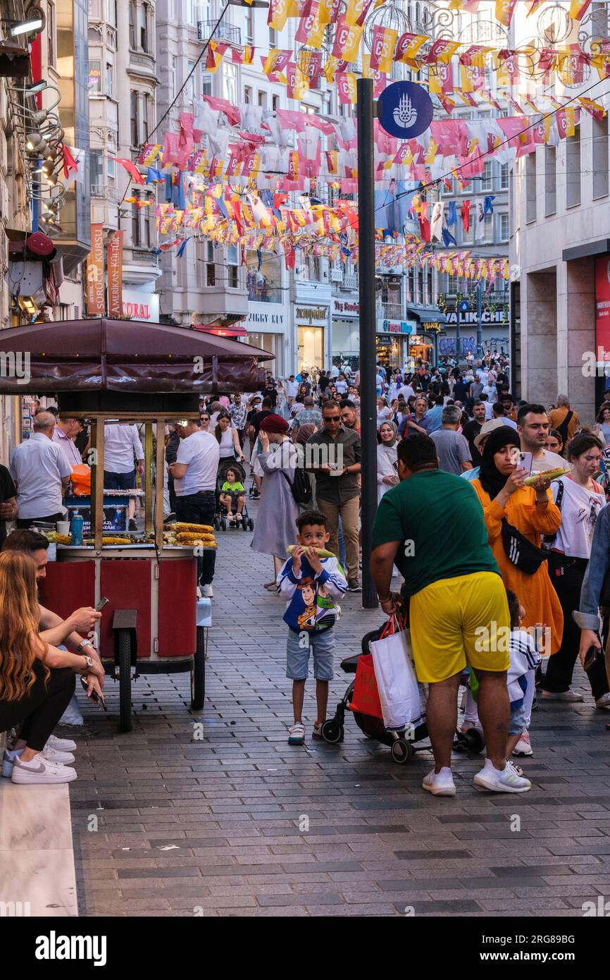 Istanbul, Turchia, Türkiye. Istiklal Street, famiglia che compra mais arrosto sul Cob per bambini. Foto Stock