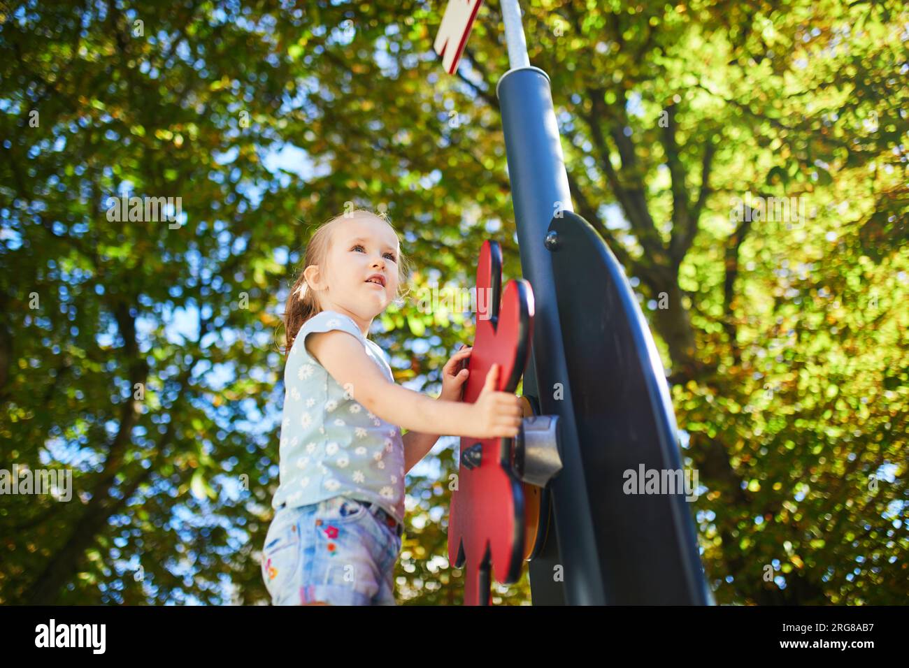 Adorabile bambina al parco giochi in una giornata di sole. Bambini in età prescolare che giocano all'aperto. Attività estive all'aperto per bambini Foto Stock