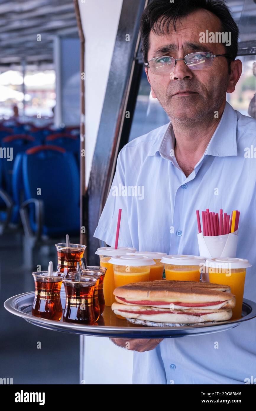 Istanbul, Turchia, Turkiye. Venditore di tè e succo d'arancia su un traghetto per pendolari. Foto Stock