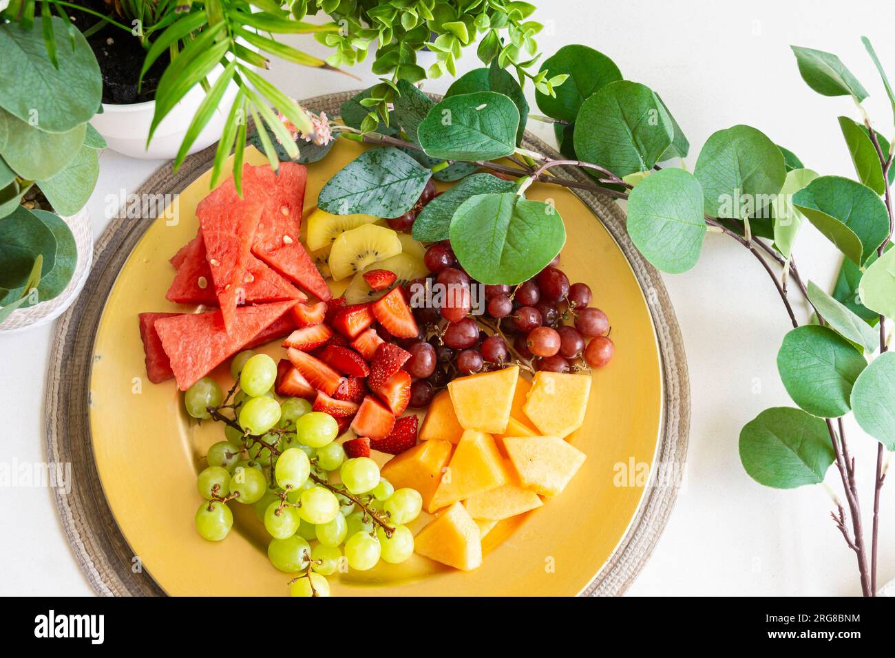 Frutta vibrante splendidamente disposta su un piatto dorato, per creare uno spuntino o un dessert salutare e rinfrescante Foto Stock