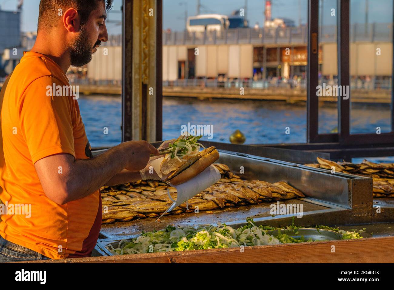 Istanbul, Turchia, Turkiye. Cucina il pesce fritto, prepara i sandwich di pesce per il ristorante sul lato della barca vicino al ponte Galata, Eminonu. Foto Stock