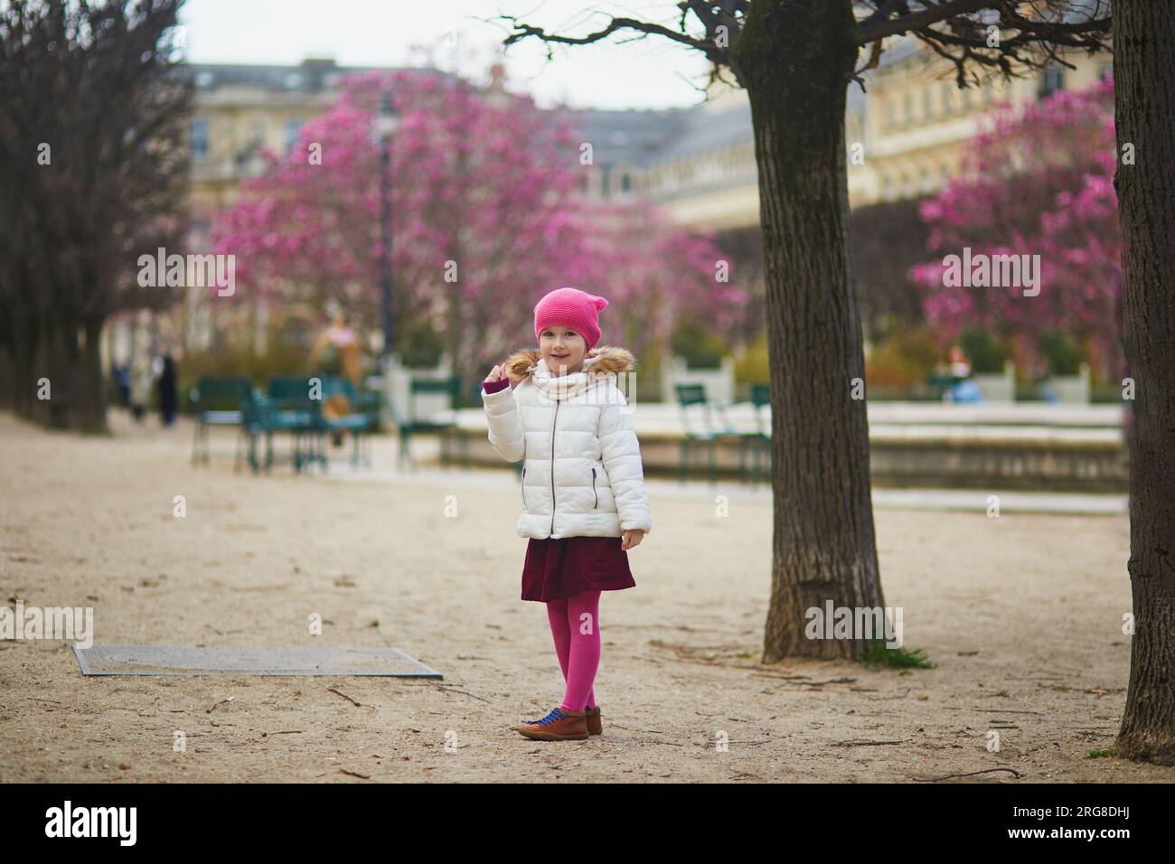 Allegra bambina in età prescolare che si diverte in una strada di Parigi, Francia all'inizio della primavera, con magnolie rosa in fiore Foto Stock