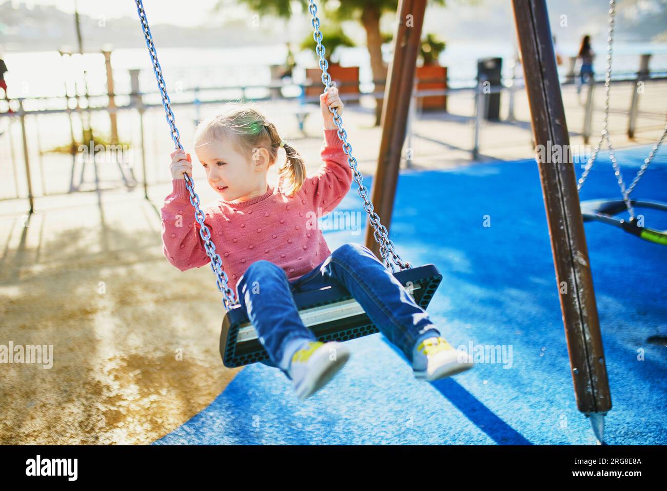 Felice bambina di 4 anni su un altalena. Happy Kid al parco giochi che si snoda su una seesaw. Attività estive all'aperto per bambini Foto Stock