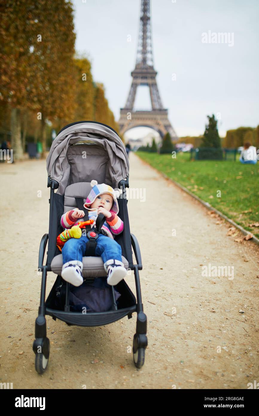 Adorabile bambina seduta in passeggino vicino alla Torre Eiffel a Parigi, Francia. Viaggiare con i bambini Foto Stock