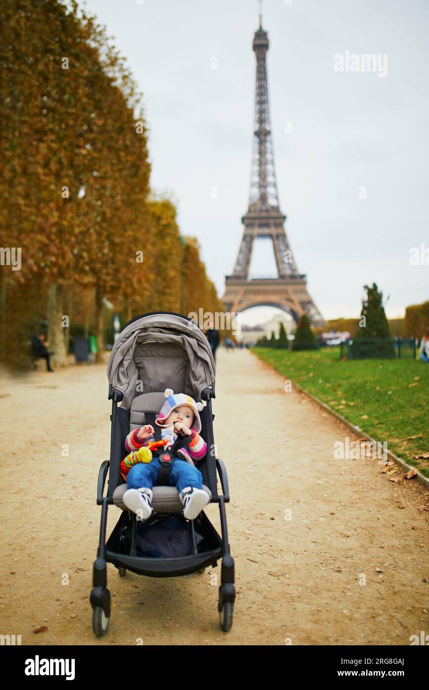 Adorabile bambina seduta in passeggino vicino alla Torre Eiffel a Parigi, Francia. Viaggiare con i bambini Foto Stock