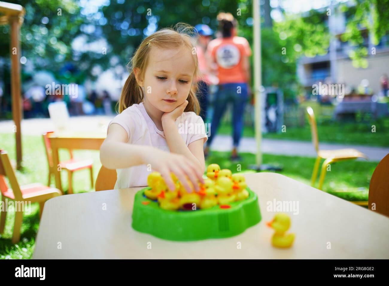 Adorabile bambina in età prescolare che gioca a un gioco da tavolo all'aperto Foto Stock