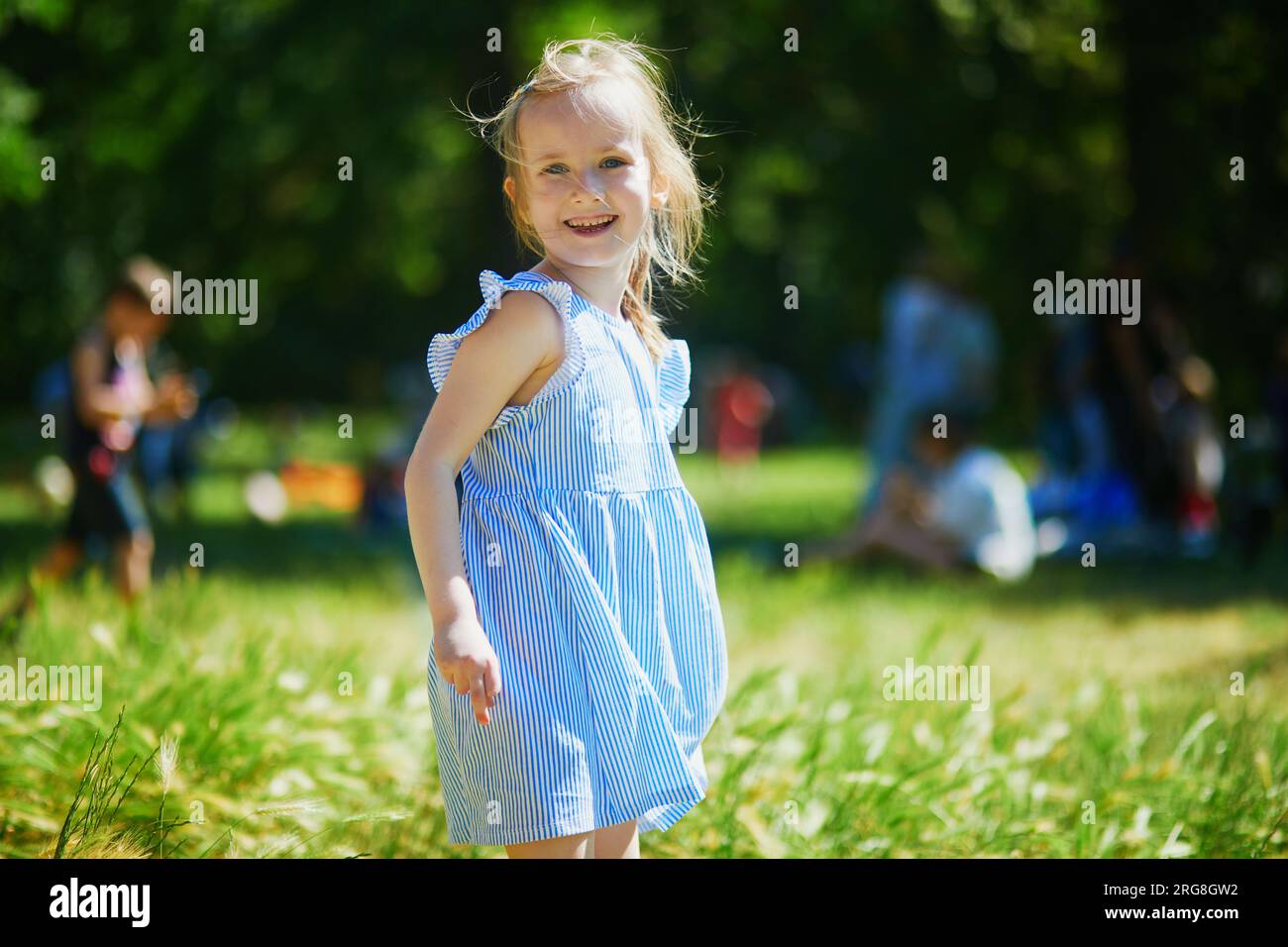 Allegra e allegra bambina che cammina nel parco. Attività estive all'aperto per bambini Foto Stock