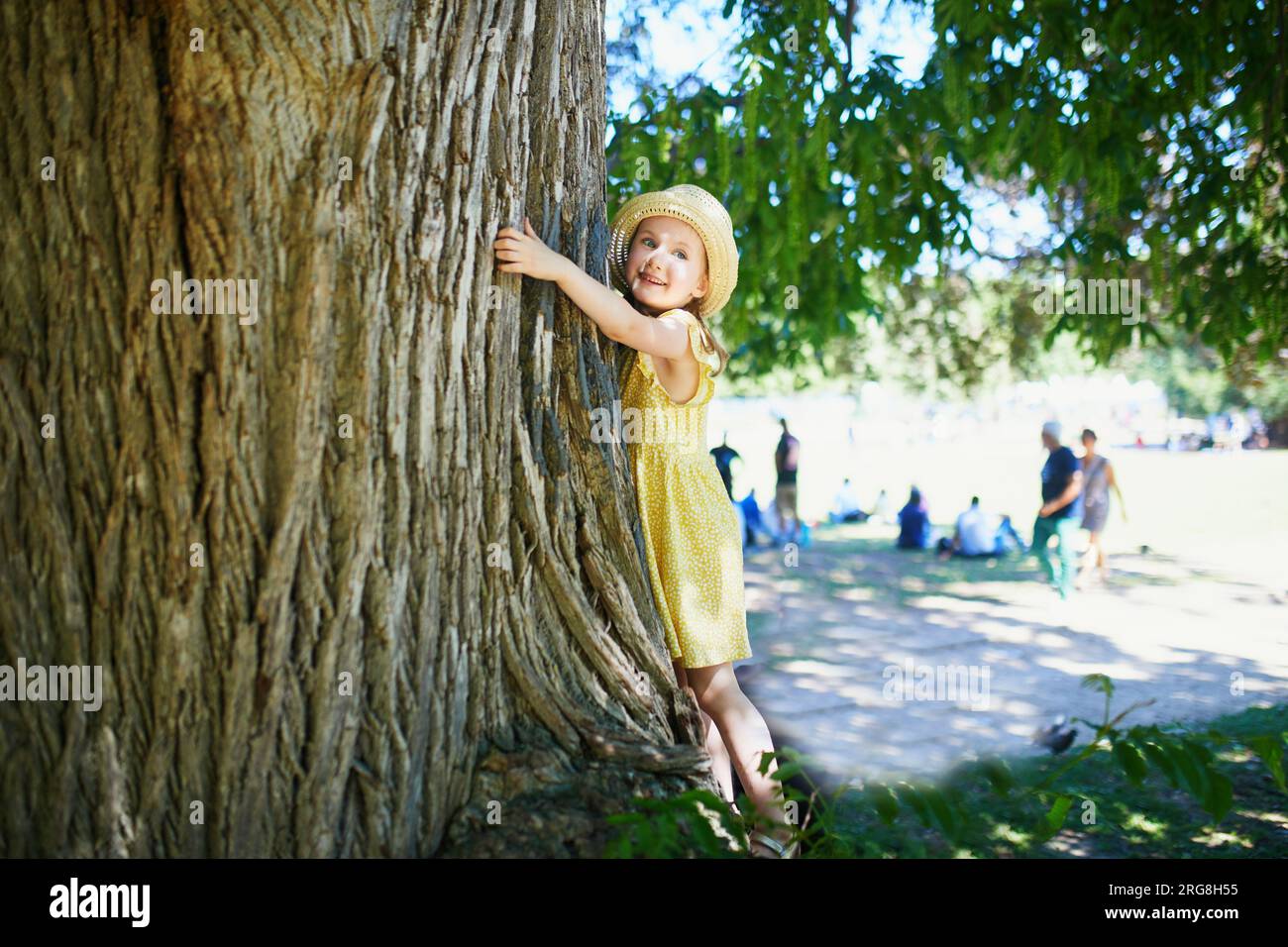 Simpatica bambina in età prescolare che gioca all'aperto nel parco o nella foresta in un giorno d'estate. Attività all'aperto per bambini Foto Stock