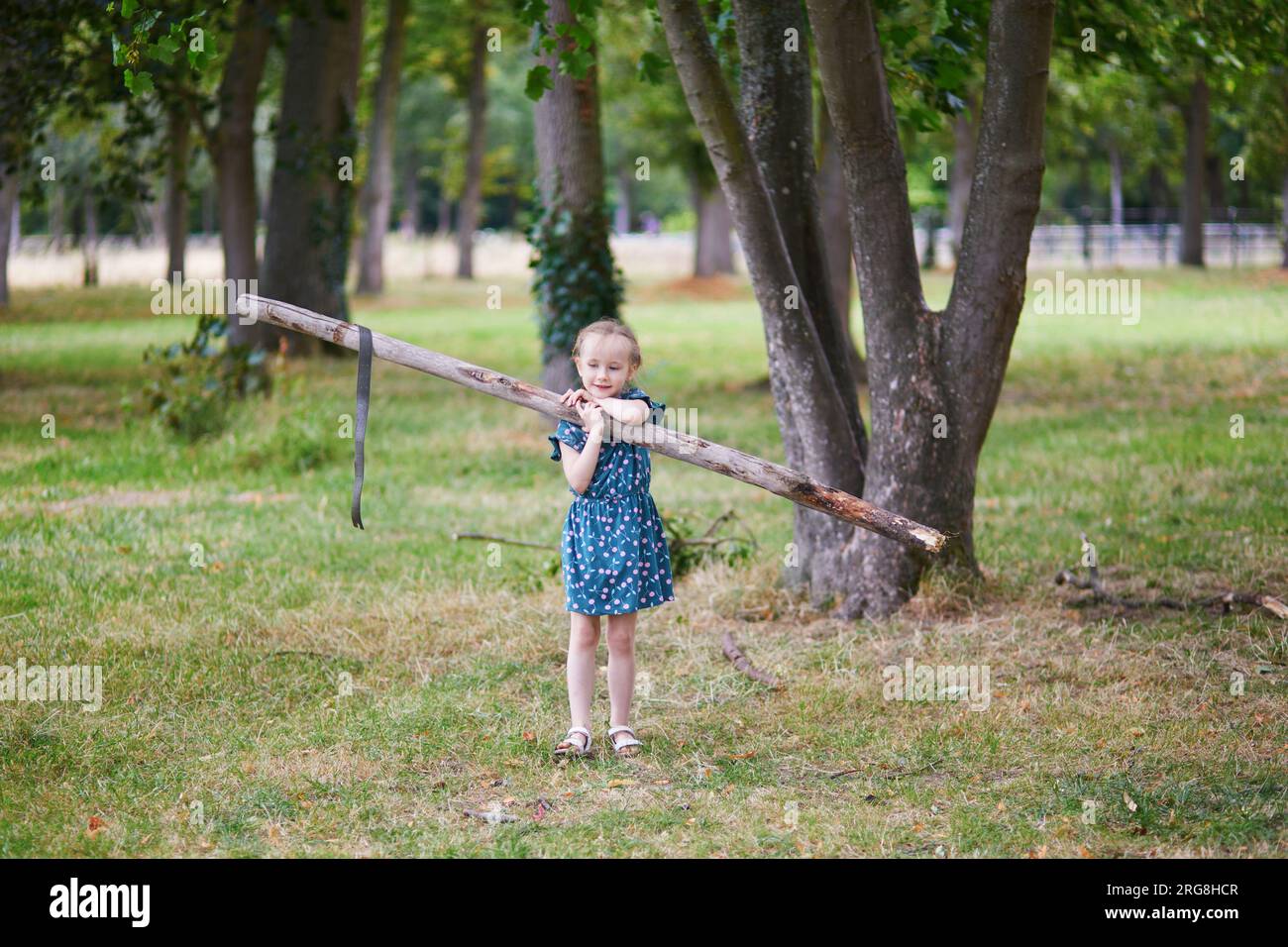 Simpatica bambina in età prescolare che gioca all'aperto nel parco o nella foresta in un giorno d'estate. Attività all'aperto per bambini Foto Stock