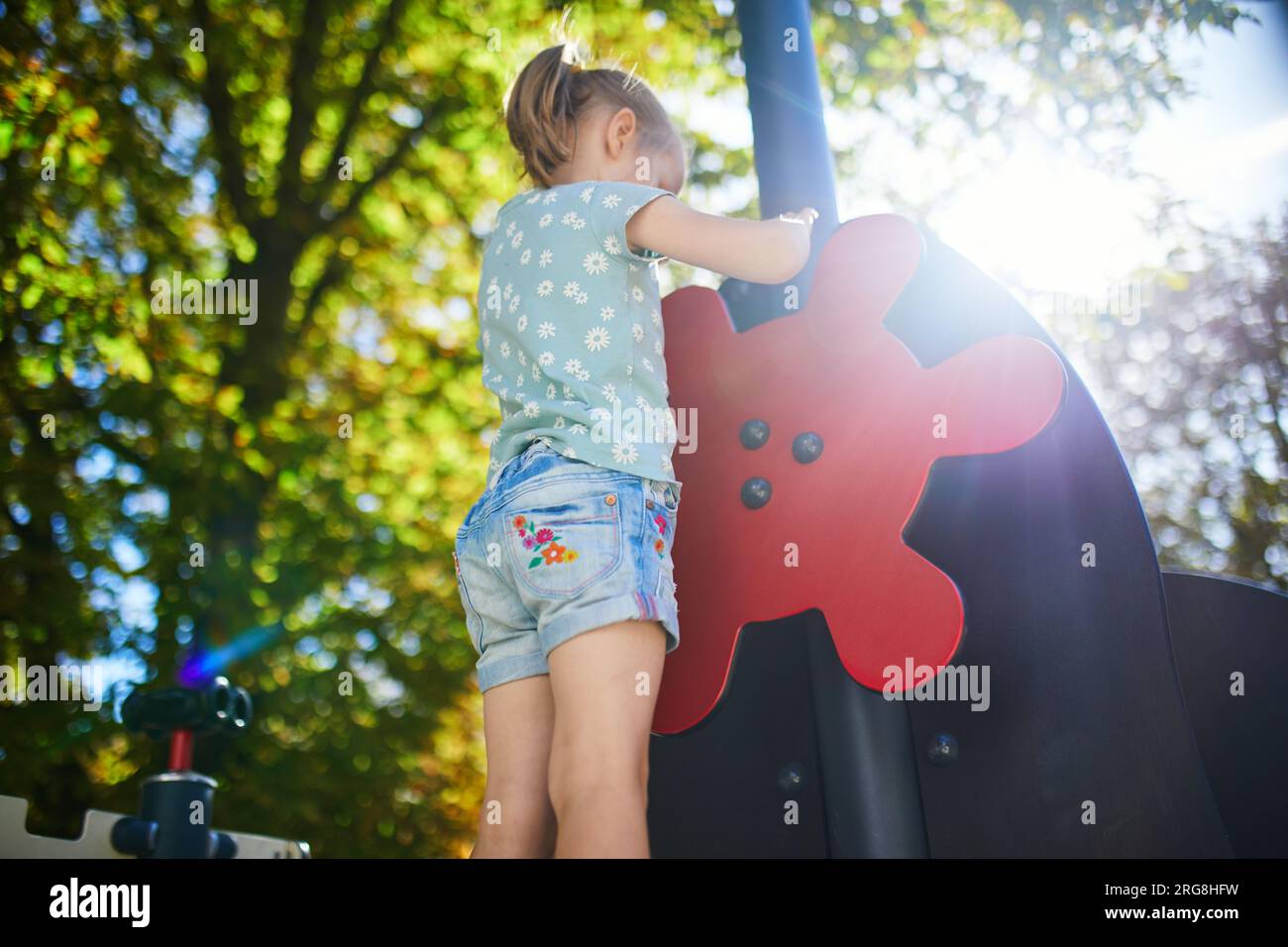 Adorabile bambina al parco giochi in una giornata di sole. Bambini in età prescolare che giocano all'aperto. Attività estive all'aperto per bambini Foto Stock