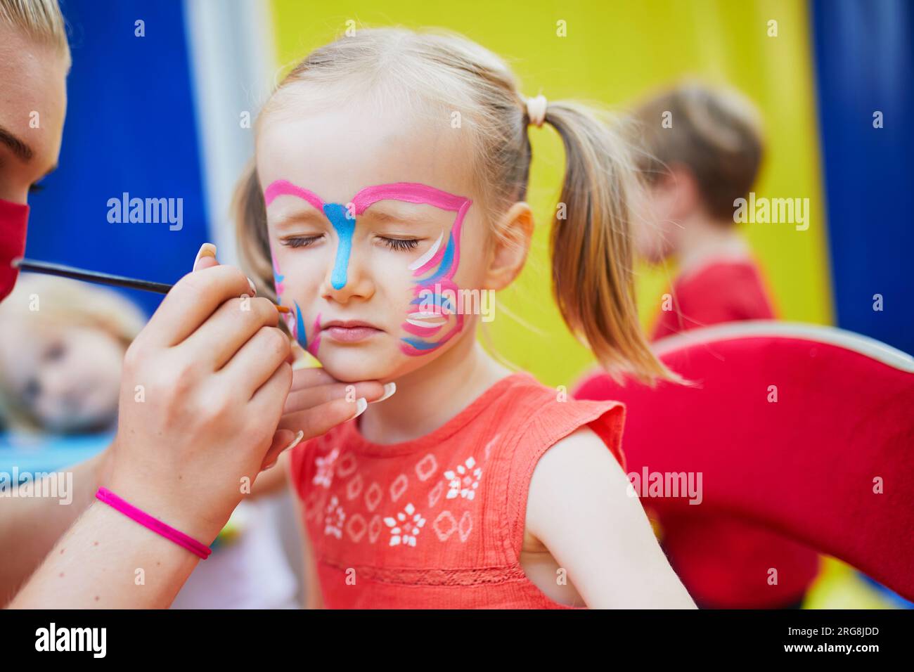 I bambini dipingono il viso. Artista che dipinge la piccola bambina della scuola materna come una farfalla. Attività creative per bambini Foto Stock