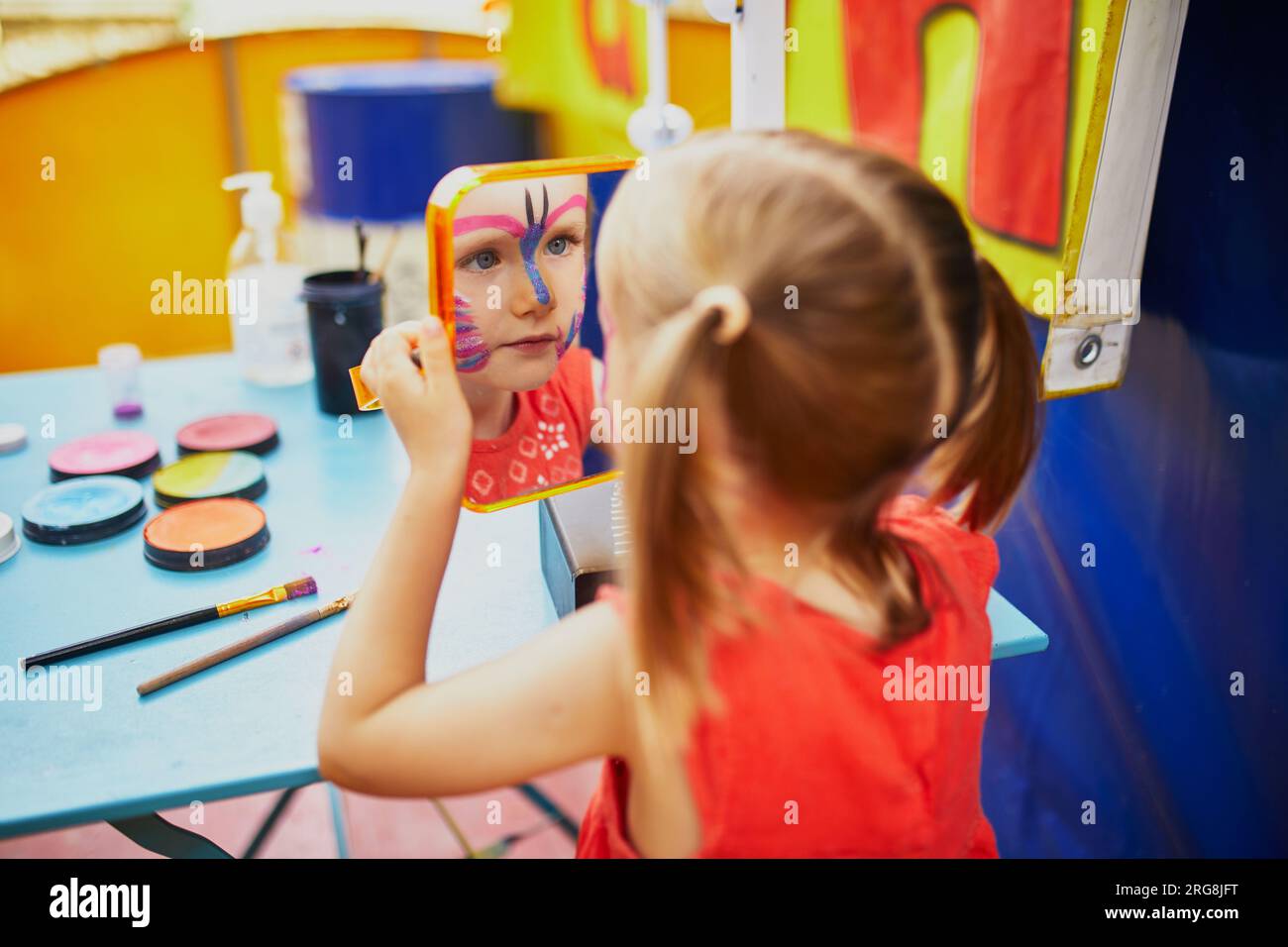 I bambini dipingono il viso. Artista che dipinge la piccola bambina della scuola materna come una farfalla. Attività creative per bambini Foto Stock