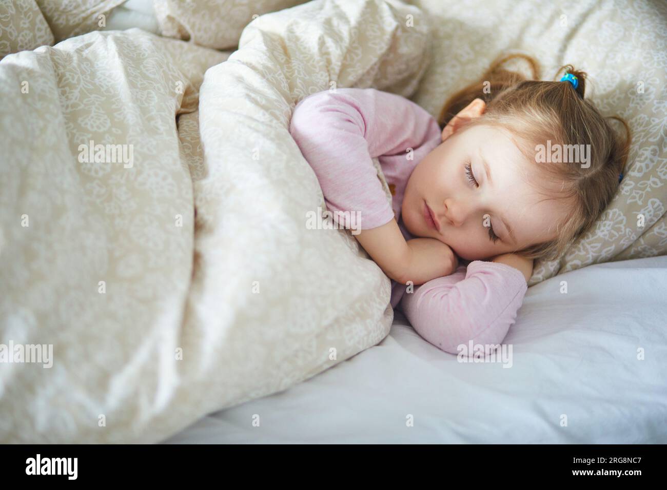 Adorabile bambina in età prescolare che fa un pisolino di un giorno. Bambino piccolo che dorme a letto. Concetto per dormire Foto Stock