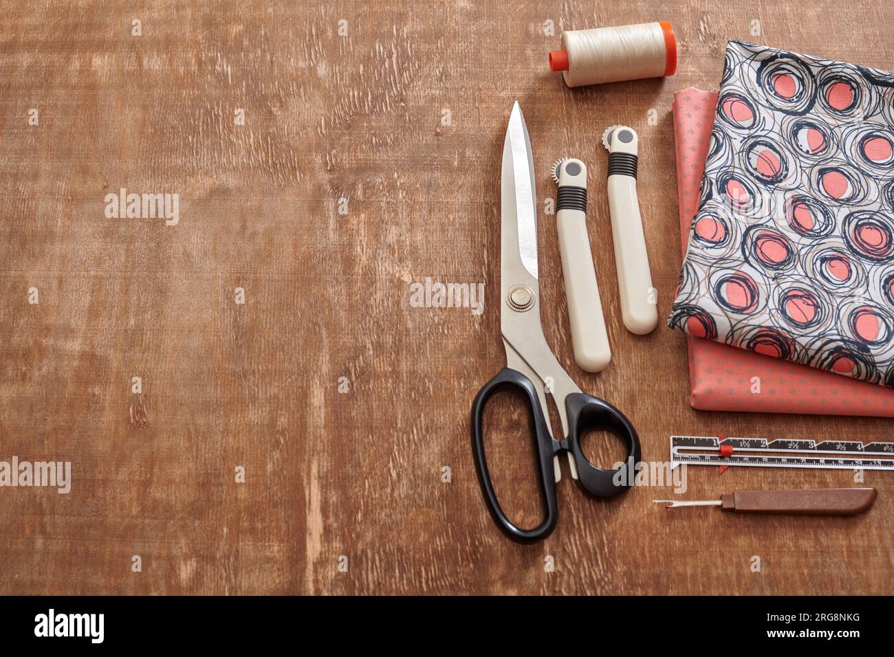 Accessori per cucire e tessuti su una superficie in legno Foto Stock