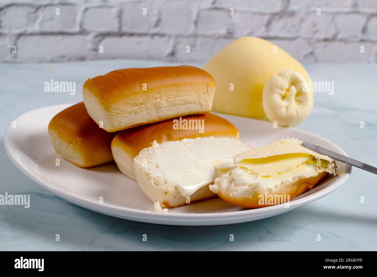 Alcuni panini per la cena in Brasile sono chiamati "Bisnaguinha" ripieni di formaggio e formaggio spalmabile su un piatto bianco. Foto Stock
