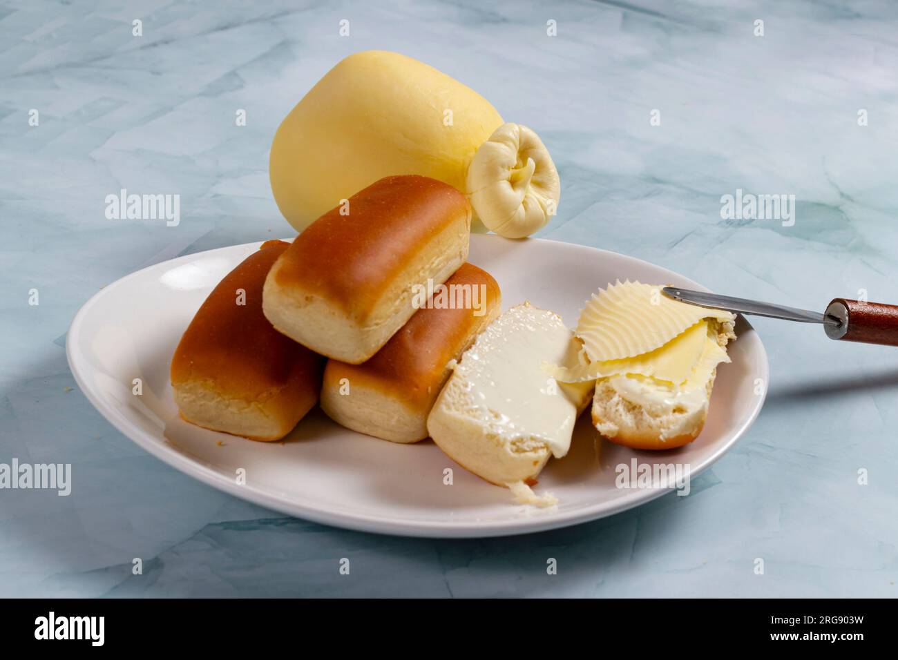 Alcuni panini per la cena in Brasile sono chiamati "Bisnaguinha" ripieni di formaggio e formaggio spalmabile su un piatto bianco. Foto Stock