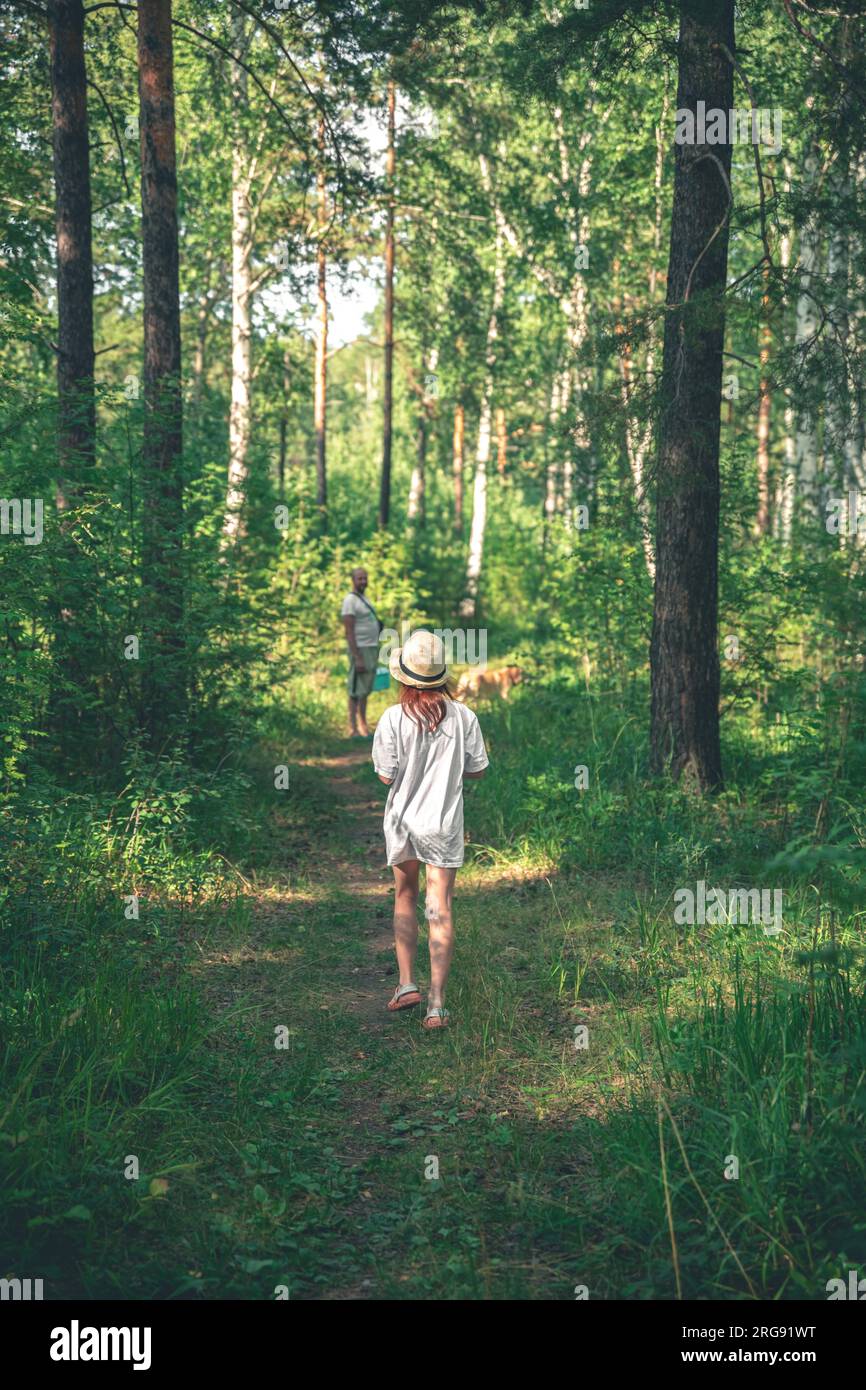bella ragazza con bastone nella foresta in cerca di funghi Foto Stock