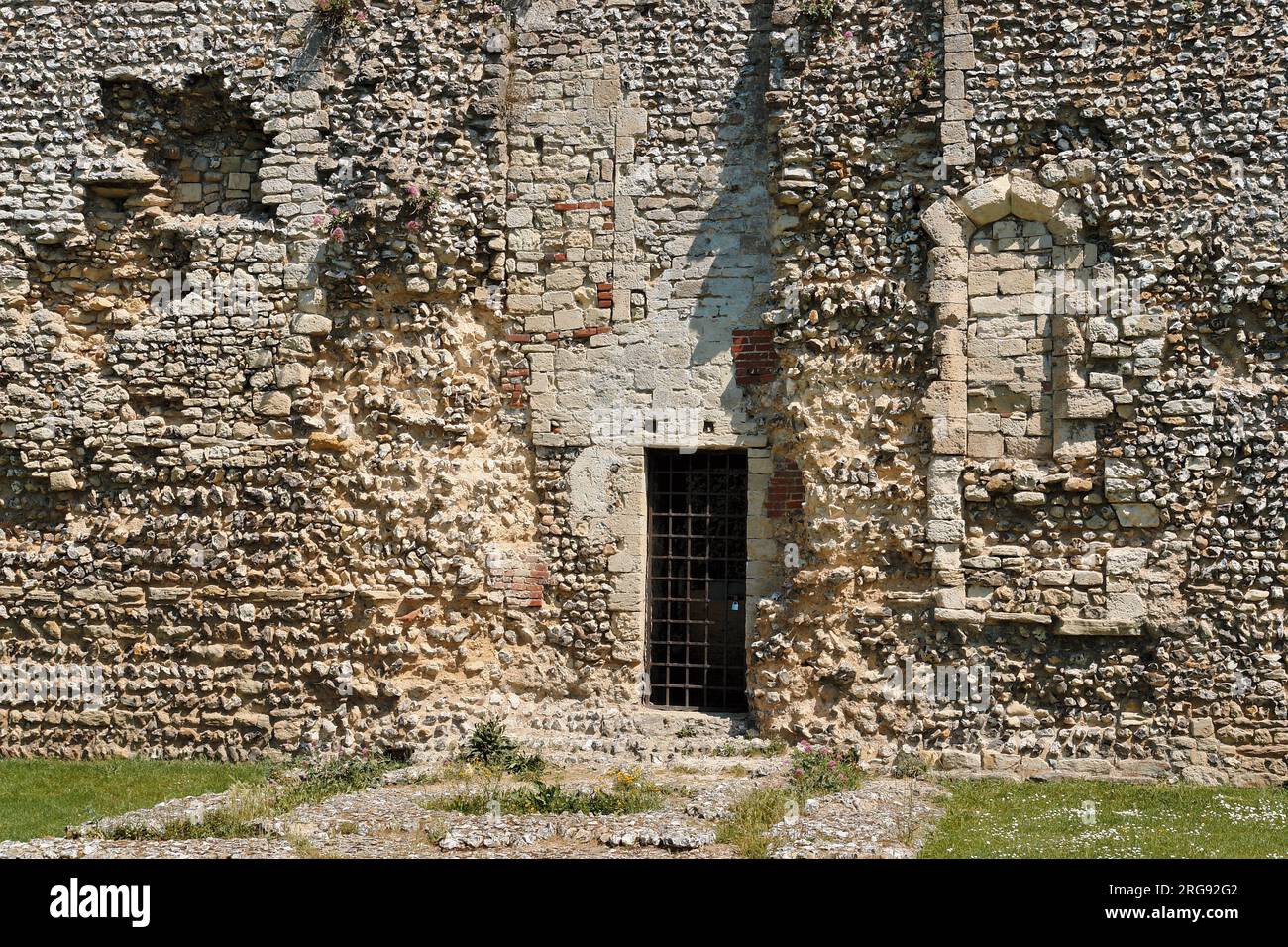 Vista ravvicinata della variegata muratura del castello di Portchester, vicino a Portsmouth, Hampshire, che mostra come l'edificio sia stato aggiunto nel corso dei secoli. Costruito come forte romano alla fine del III secolo, divenne un castello normanno nel XII secolo, Riccardo II ne trasformò parte in un palazzo nel 1396, e Enrico V partì da qui nel 1415. Foto Stock