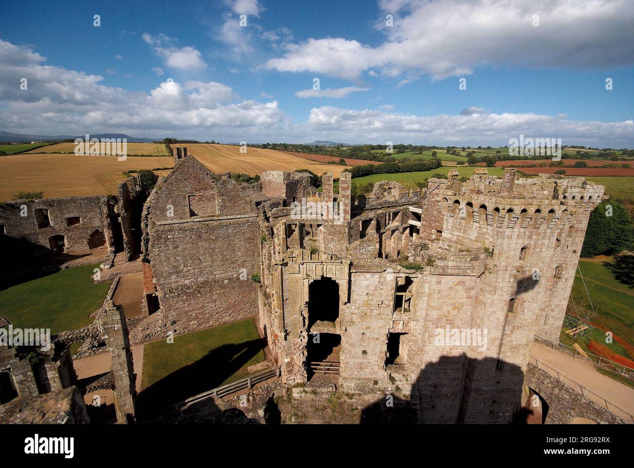 Raglan Castle vicino a Raglan, Gwent, una fortezza militare costruita nel Medioevo per difendere il confine gallese contro gli inglesi. Divenne una rovina durante la guerra civile inglese. Negli ultimi anni è stato popolare come location cinematografica e televisiva. Una vista aerea, con campi sullo sfondo. Foto Stock