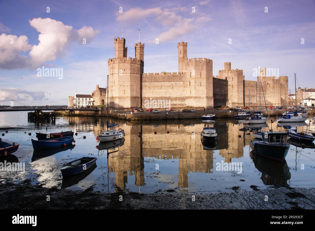 Vista del castello di Caernarfon (Caernarvon) nel Gwynedd, Galles del Nord, con numerose barche in acqua in primo piano. Il castello fu costruito dal re inglese Edoardo i intorno al 1283, sul sito di una fortezza romana e Norman motte. Foto Stock