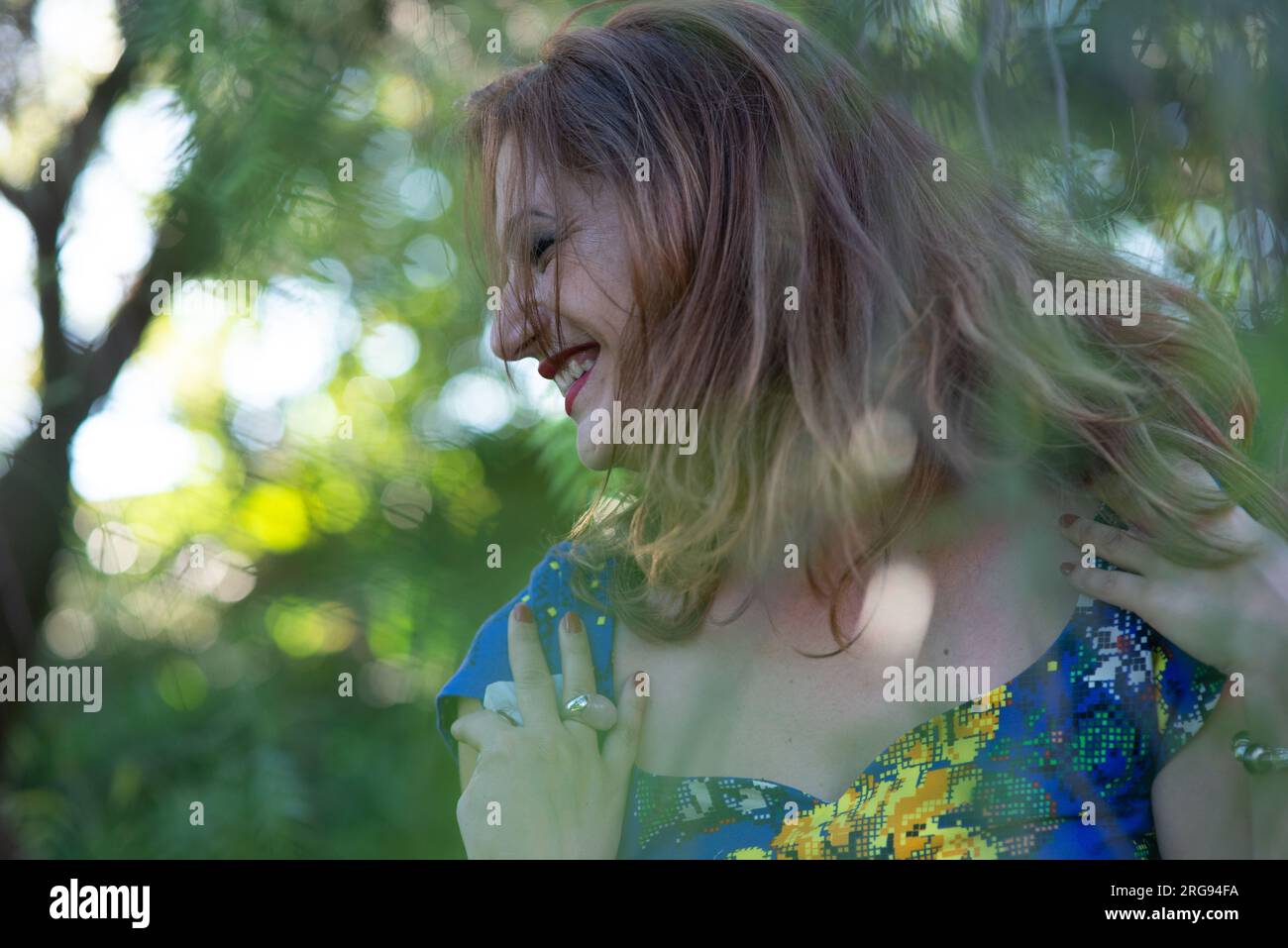 Bella donna che sorride mentre si sfreccia i capelli in natura Foto Stock