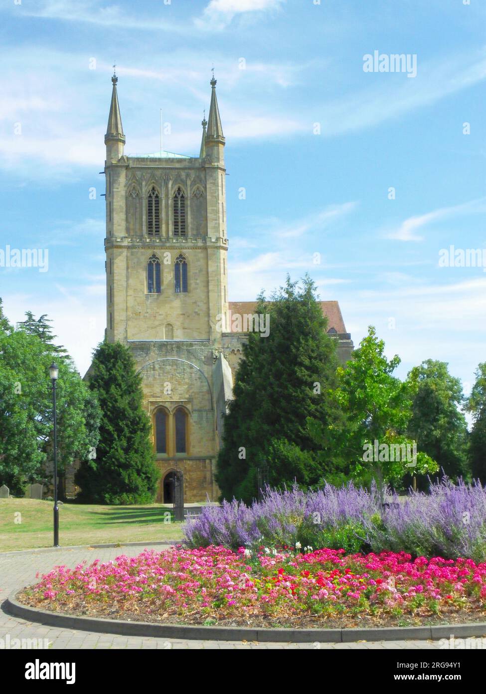 Pershore Abbey, Pershore, Worcestershire, un bell'esempio di architettura normanna e inglese, con una variopinta gamma di fiori in primo piano. Foto Stock