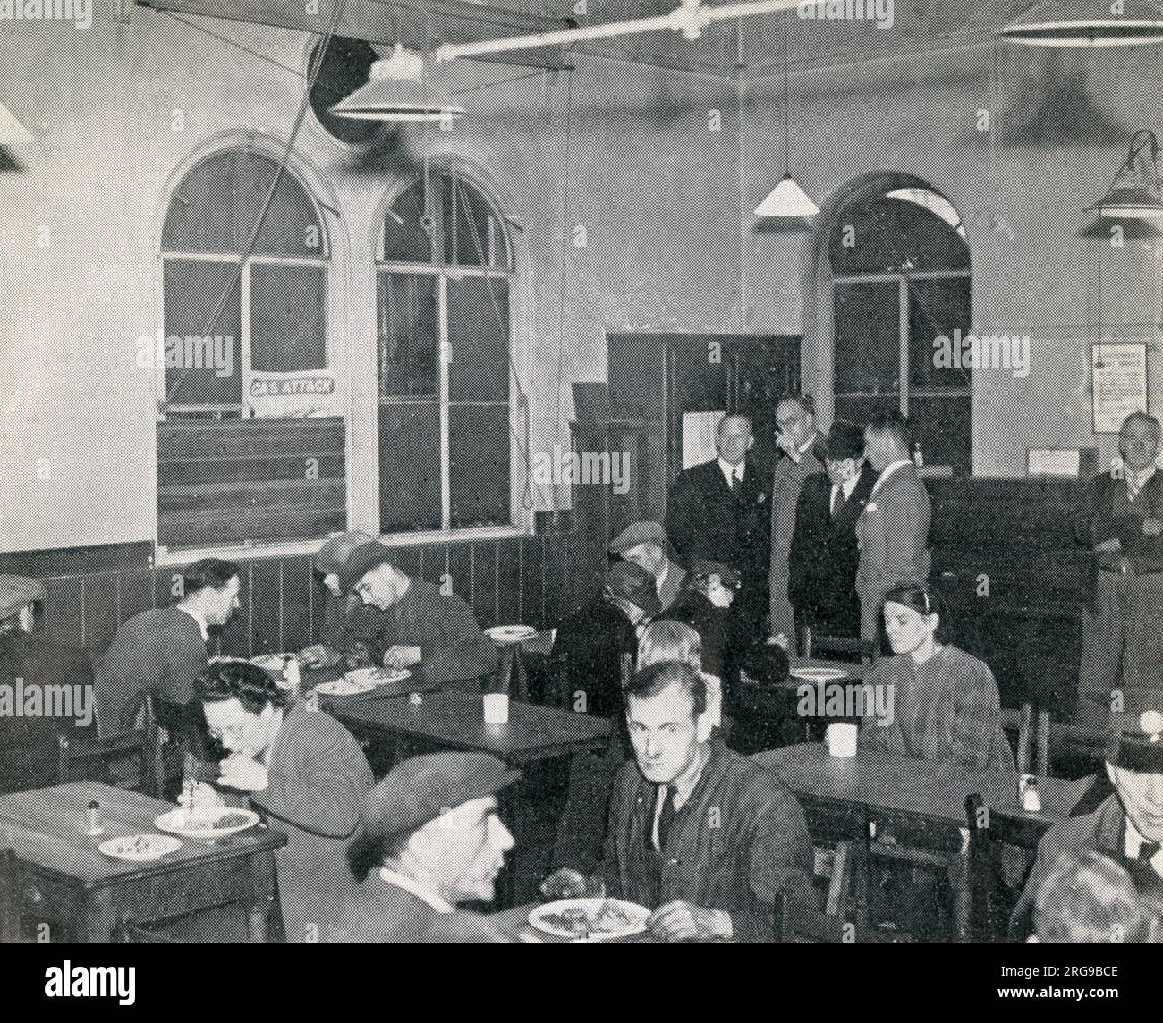 Scena all'interno del primo ristorante britannico a Woolmore Street, Poplar, East London, uno dei numerosi ristoranti comuni durante la seconda Guerra Mondiale che offre un pasto cucinato, con dessert e una tazza di tè, al costo di circa 1 s.2d. Mentre operavano su base mensa, i pasti venivano consumati a un tavolo e permettevano a persone, compresi gli operai di guerra e coloro che avevano bombardato fuori casa o che potevano avere difficoltà a cucinare o a preparare un pranzo al sacco a casa, un pasto nutriente e conveniente, che potrebbe essere mangiato in aggiunta alle razioni in tempo di guerra. Foto Stock
