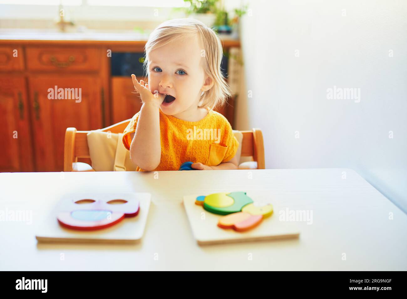 Adorabile bimba che fa puzzle di legno. I bambini imparano a risolvere i problemi e sviluppano abilità cognitive Foto Stock