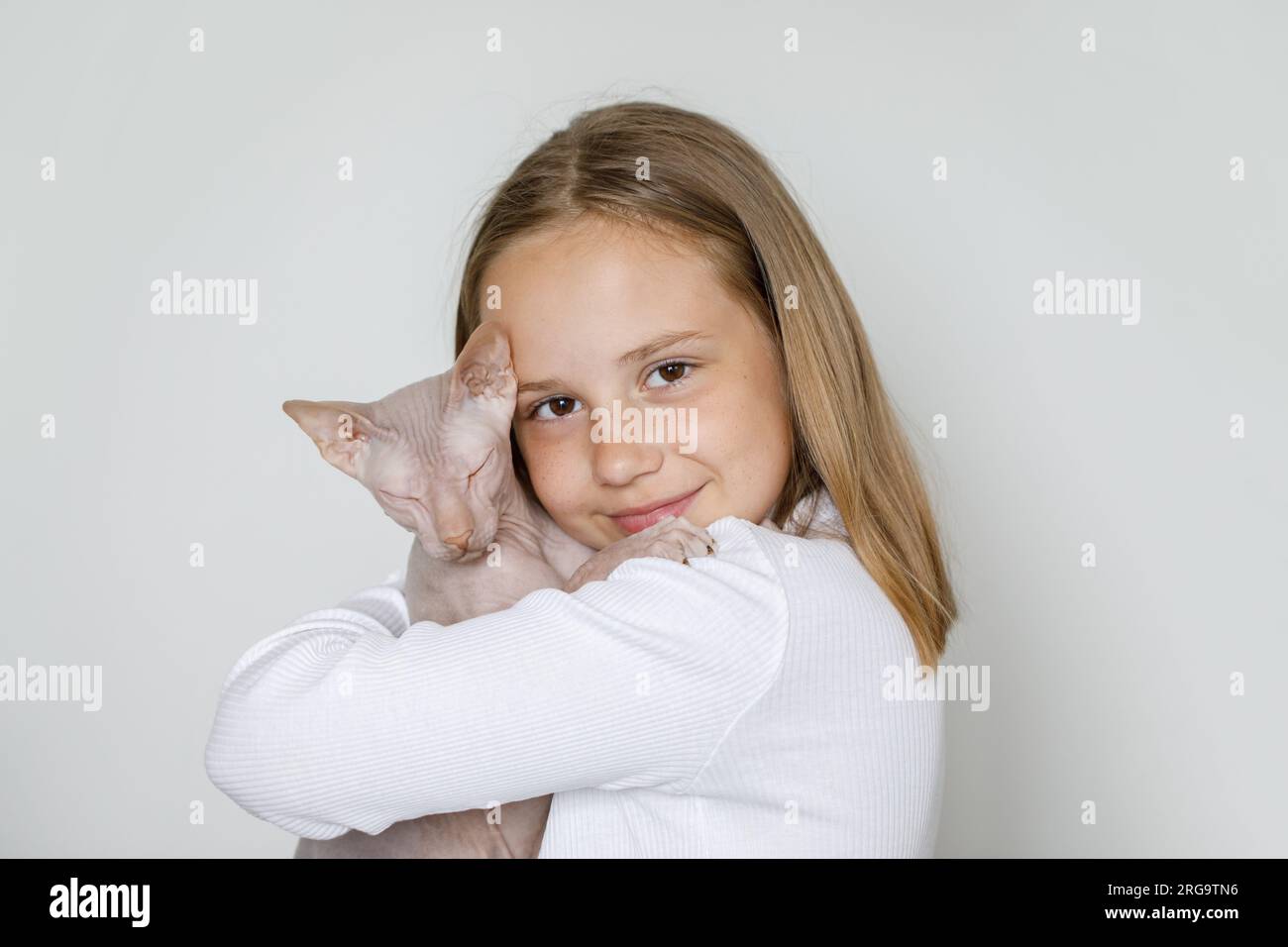 Ritratto di una bambina bruna felice e graziosa con gatto su sfondo bianco Foto Stock
