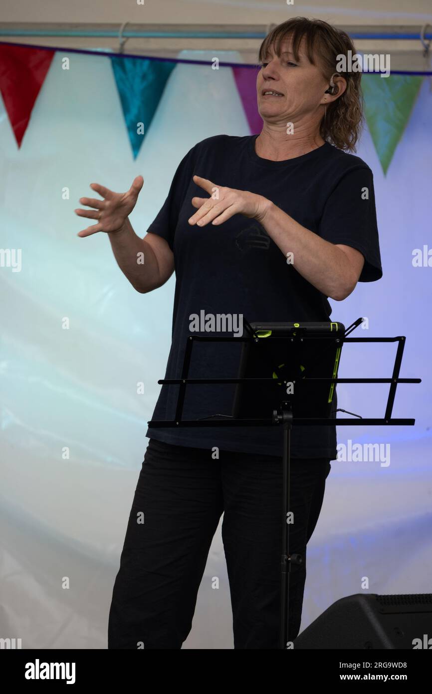 Una donna che firma per i sordi insieme a cantare all'Art in the Park, Leamington Spa, Warwickshire, Regno Unito Foto Stock