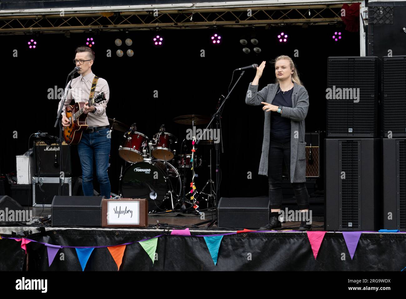 Cantante/chitarrista e donna che firma per i sordi all'Art in the Park, Leamington Spa, Warwickshire, Regno Unito Foto Stock
