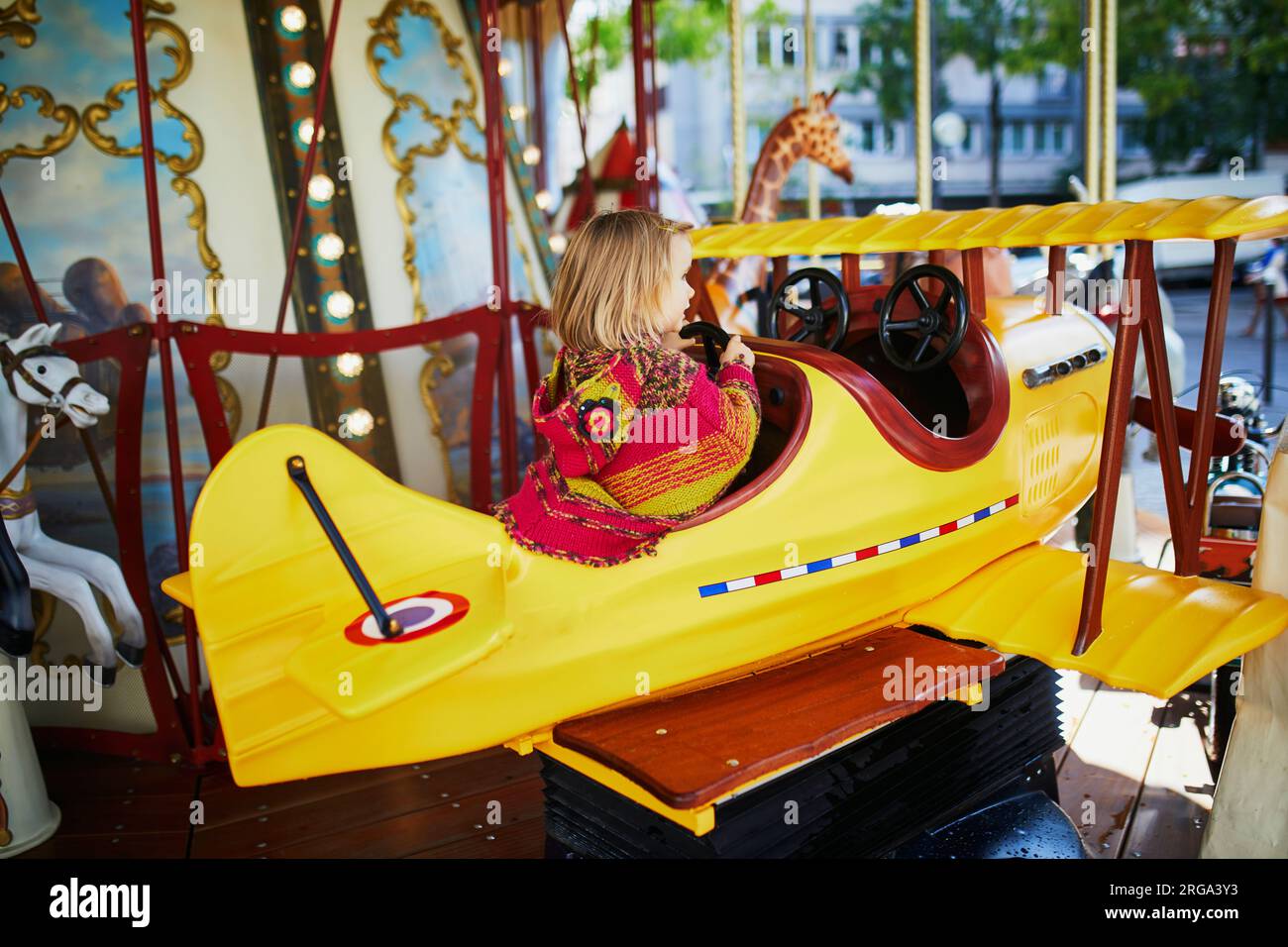 Il bambino si diverte in una giostra d'epoca francese a Parigi, in Francia. Adorabile bambina al parco giochi. Attività all'aperto per bambini piccoli Foto Stock