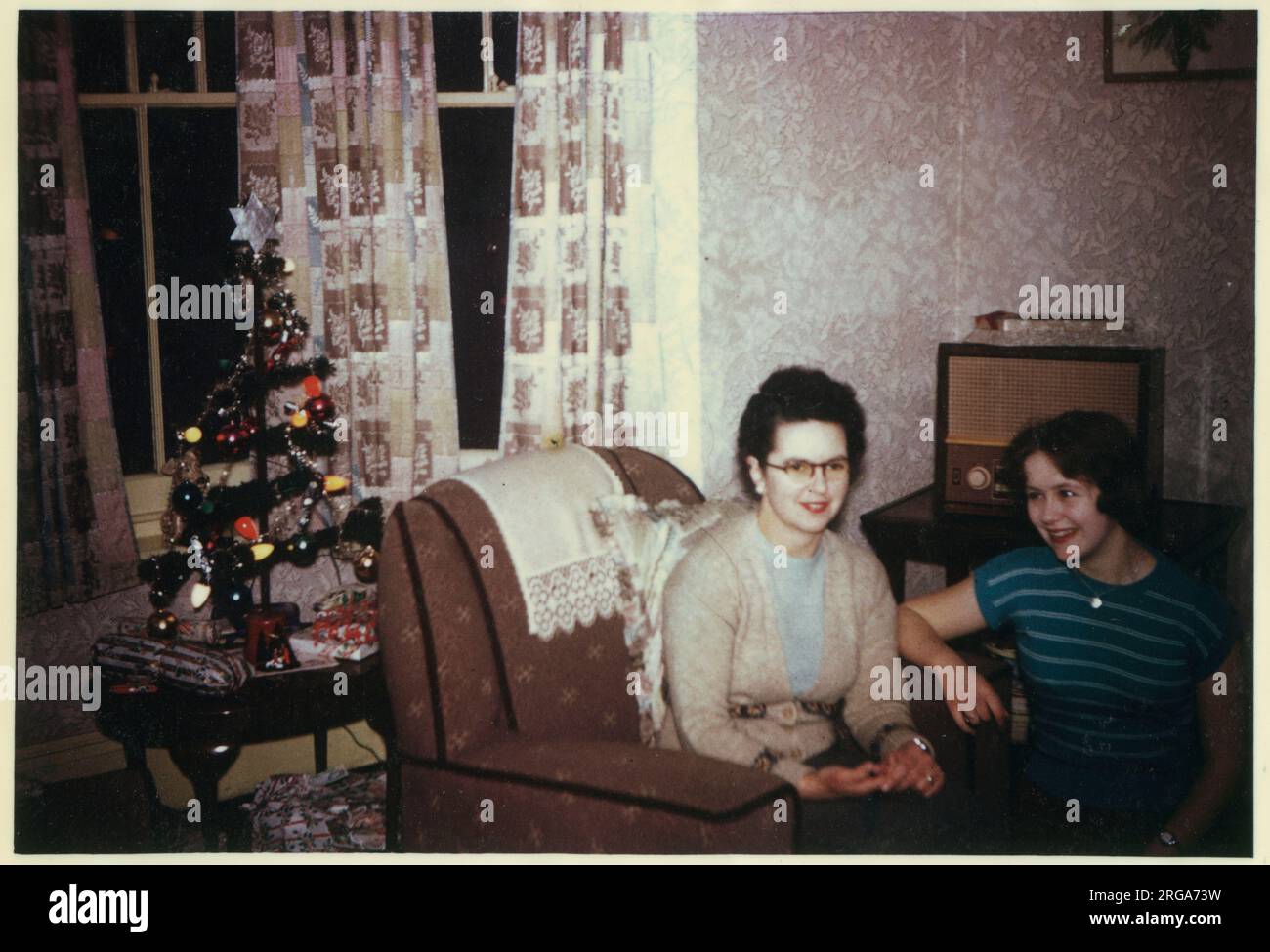 Un salotto di Natale in una casa suburbana britannica circa 1958. Una madre e la sua figlia, magari ascoltando il wireless. Foto Stock