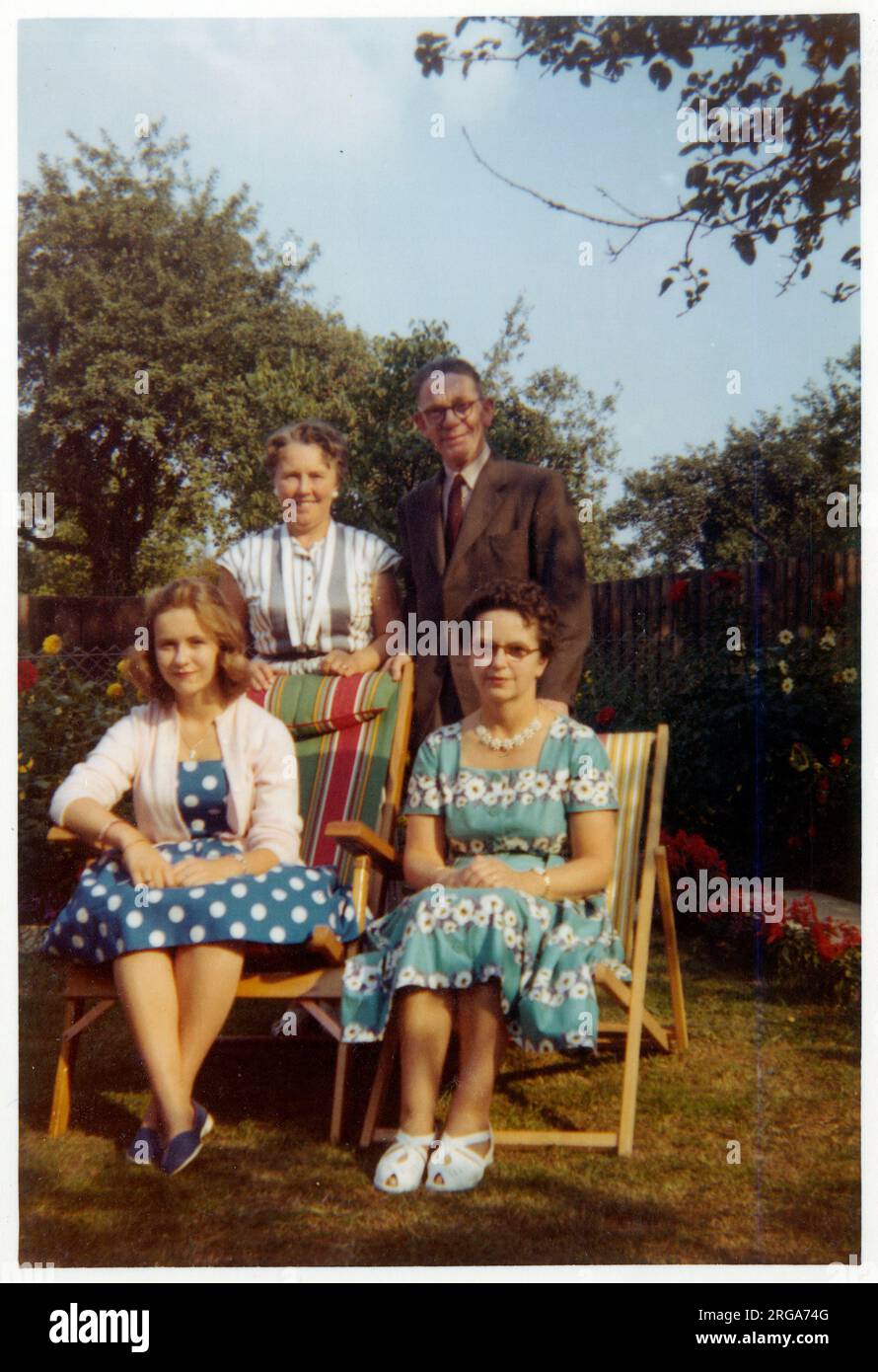 Un gruppo familiare di Madre, figlia, zio e zia - in giardino / sedie a sdraio in un elegante giardino suburbano nel tardo pomeriggio luce - settembre, 1959 Foto Stock