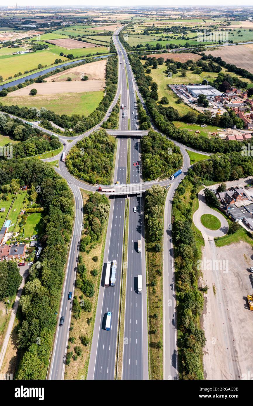 Panorama aereo verticale direttamente sopra un trafficato incrocio stradale che attraversa la campagna sull'autostrada M62 in direzione est verso Hull nel Regno Unito Foto Stock
