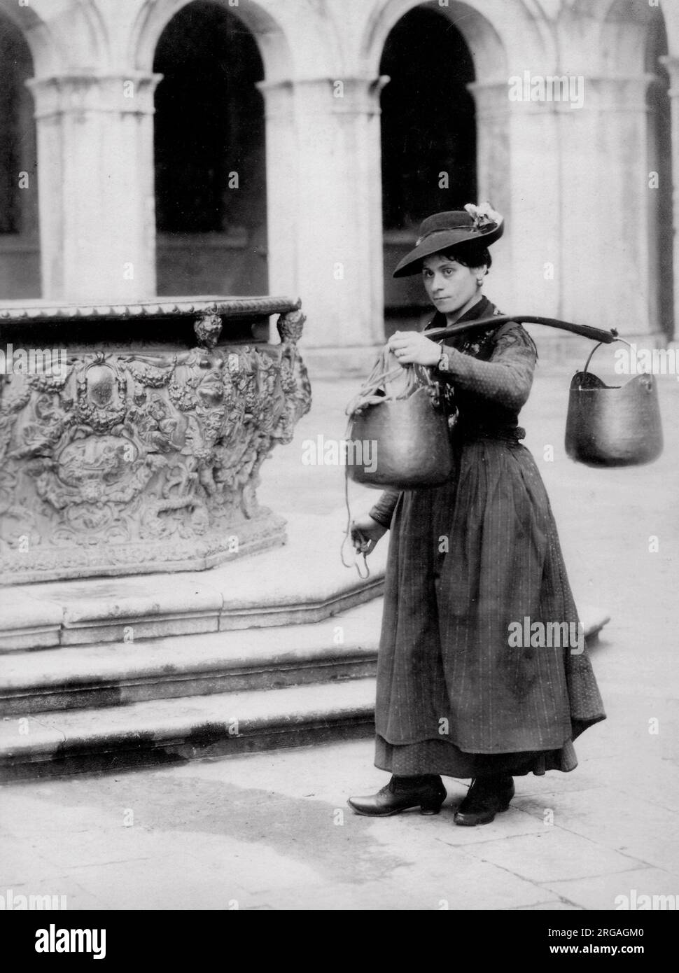 Fotografia d'annata del XIX secolo: Portatore d'acqua femminile a un pozzo, Venezia, Italia. Foto Stock