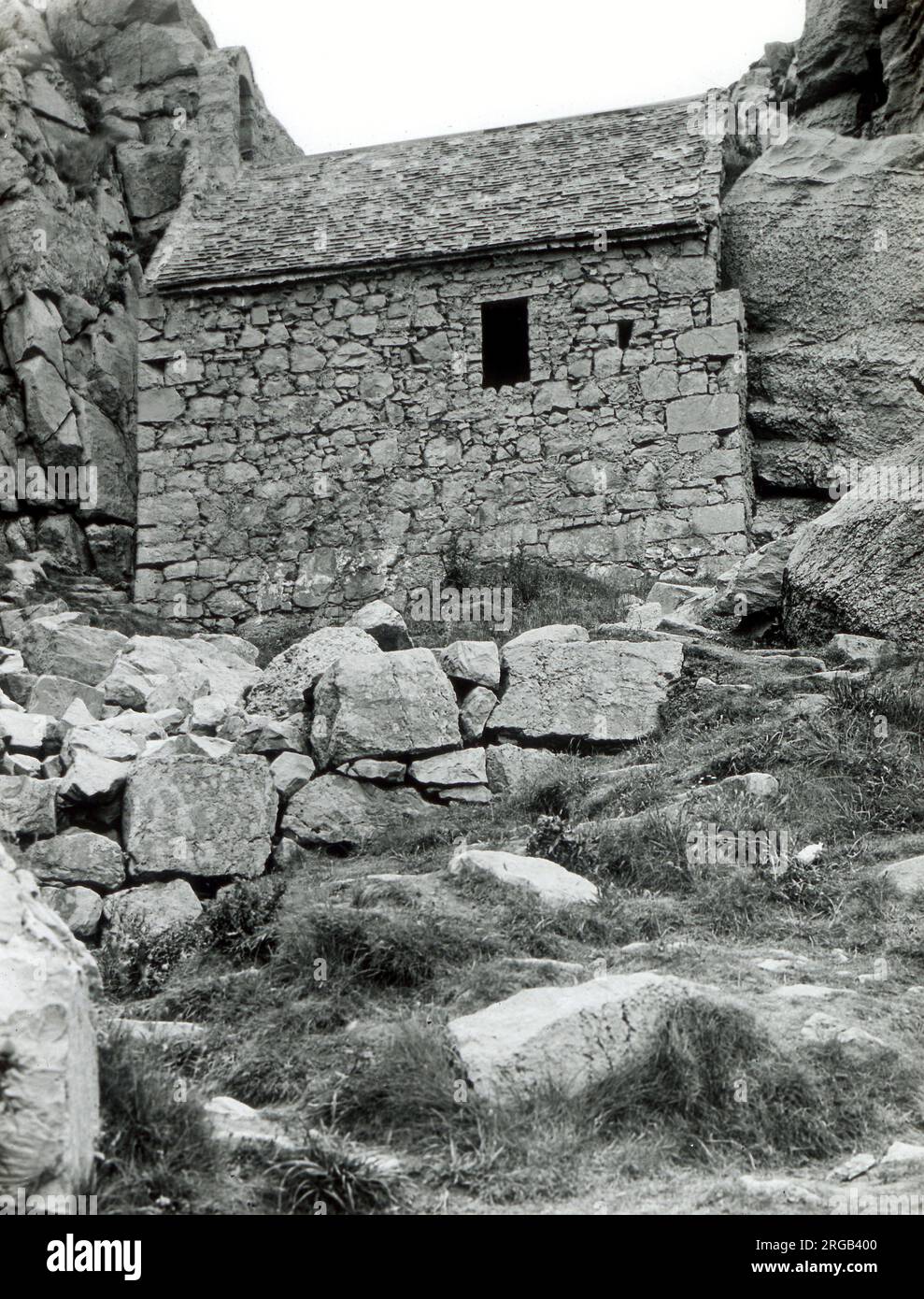 Incastonata in una nicchia, in parte giù per la scogliera a Castlemartin, è l'antica chiesa di St Govan, Pembrokeshire, Galles del Sud. Foto Stock