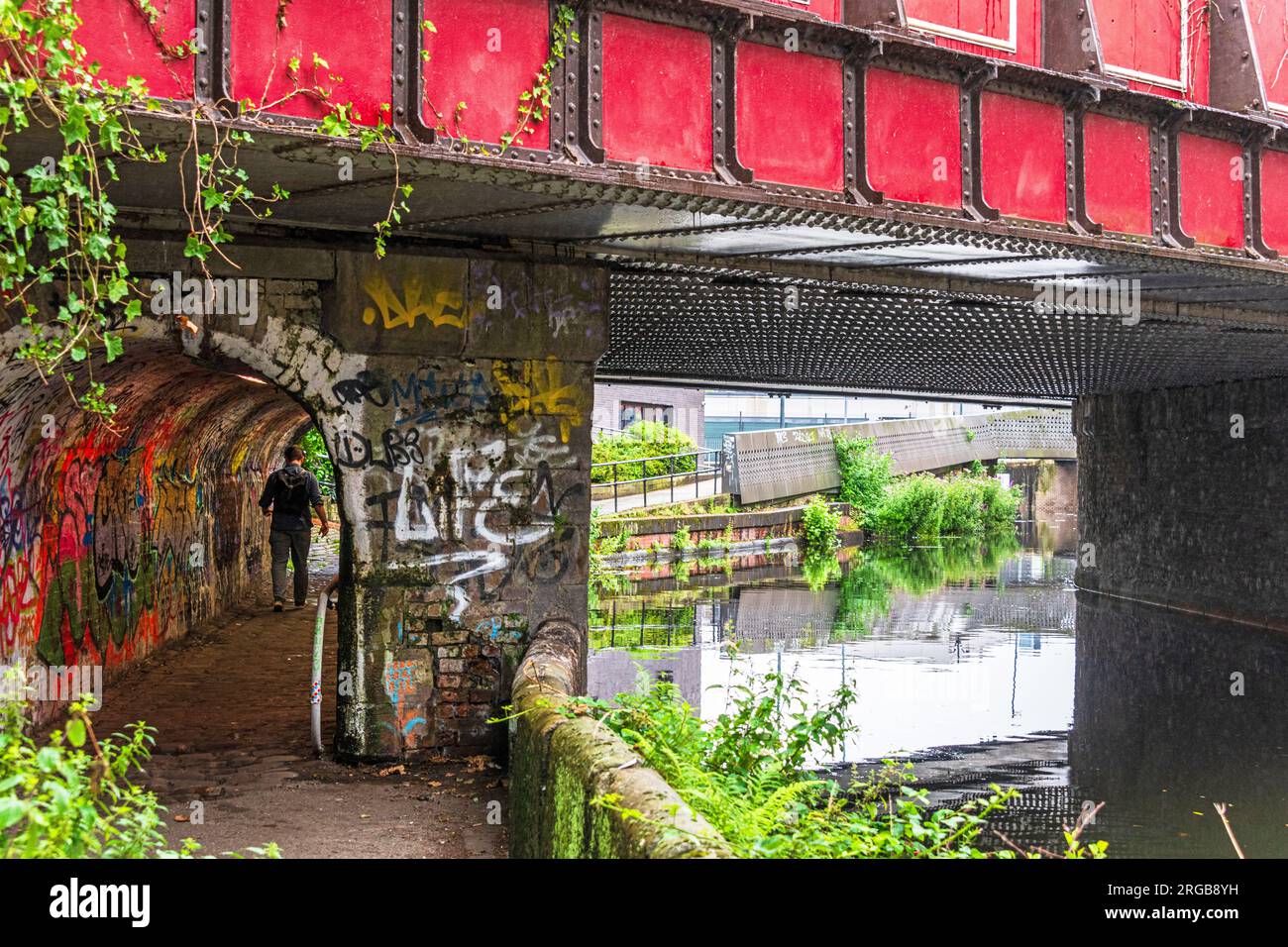 Un uomo solitario cammina attraverso il tunnel pedonale lungo il Rochdale Canal ad Ancoats Manchester. Foto Stock